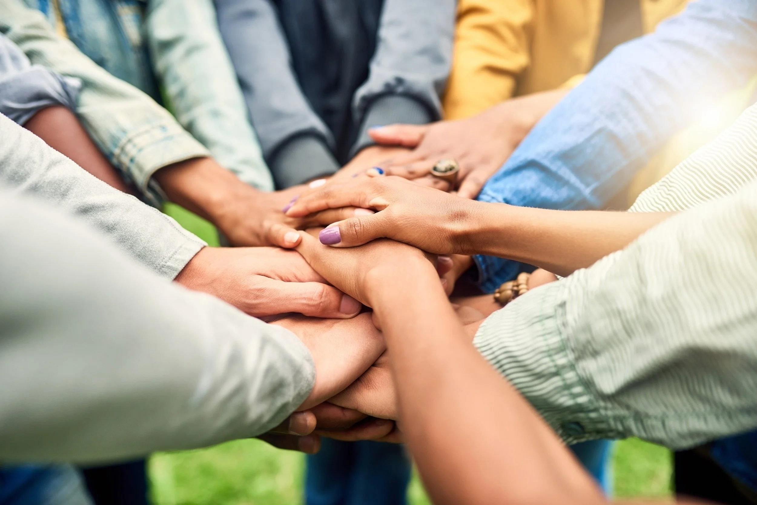 Group of diverse people placing their hands together in a show of unity.