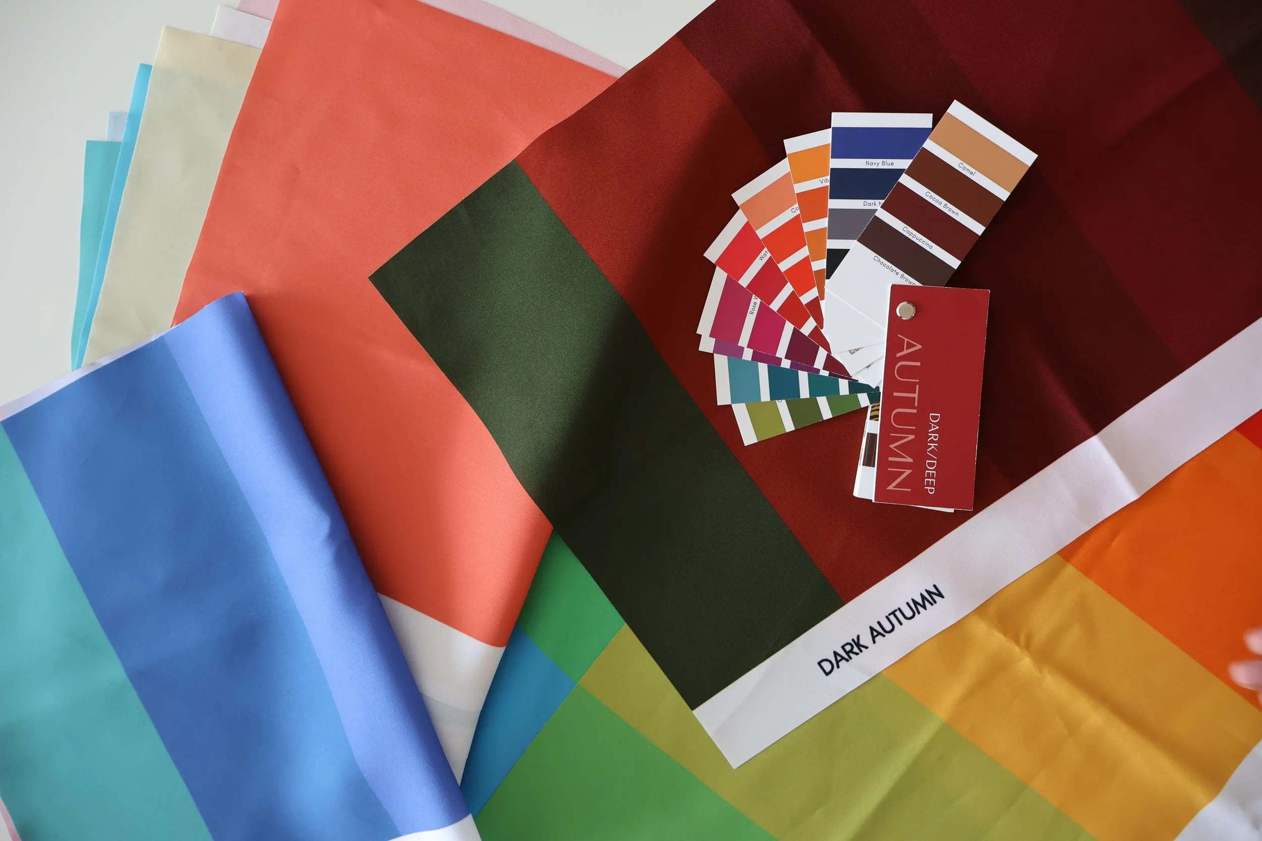 Colorful paper swatches arranged in a fan shape, with a color matching guide and labels for 'Dark Autumn' and 'Autumn' colors.