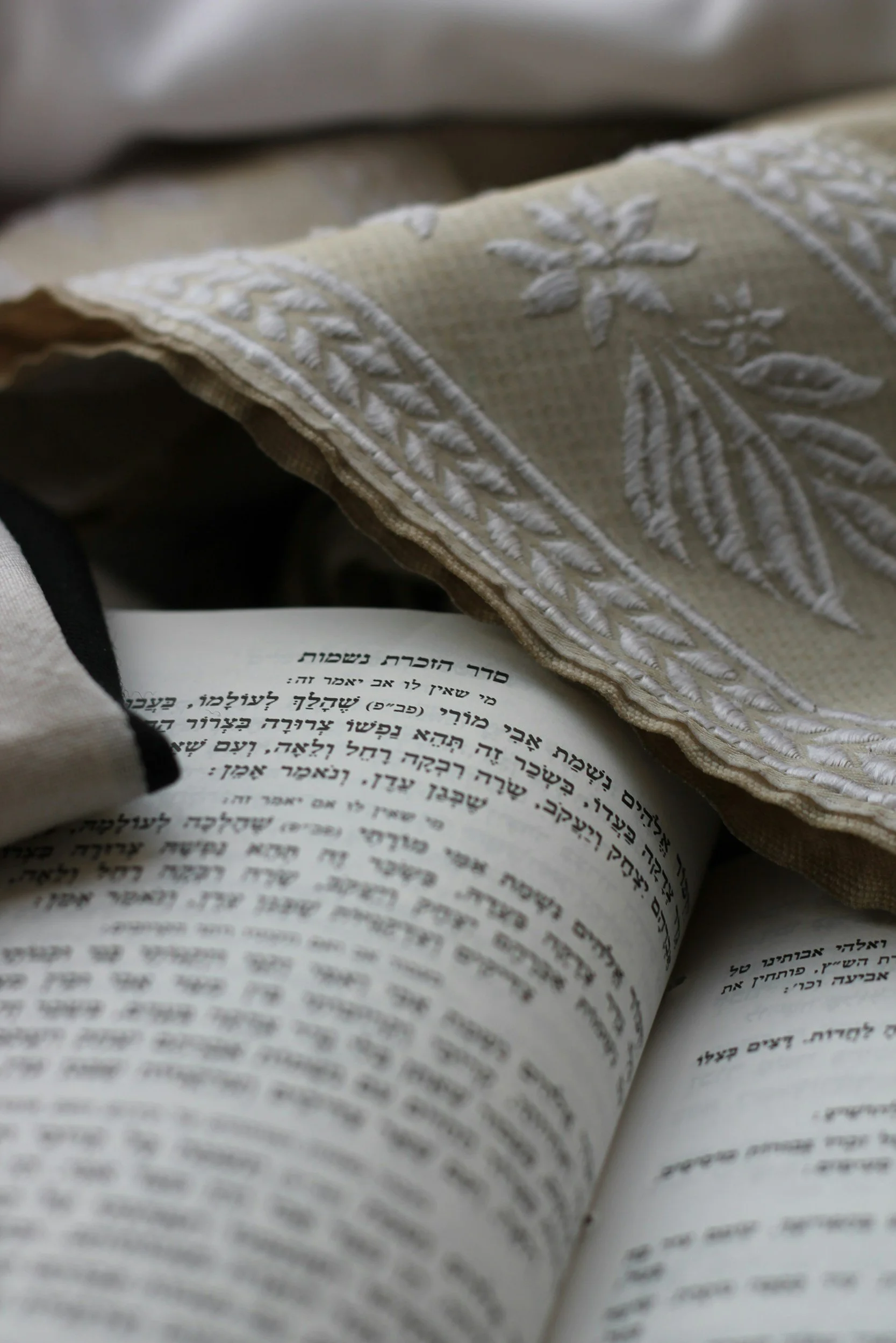 Close-up of an open Hebrew Bible with embroidered fabric covering part of the page.