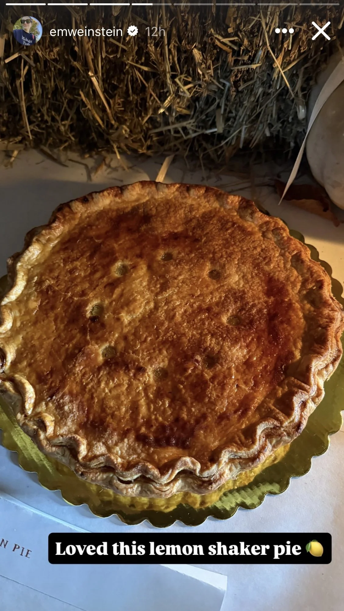 A shaker lemon pie with a golden, flaky crust and a slightly uneven, textured top crust, resting on a metallic gold tray.