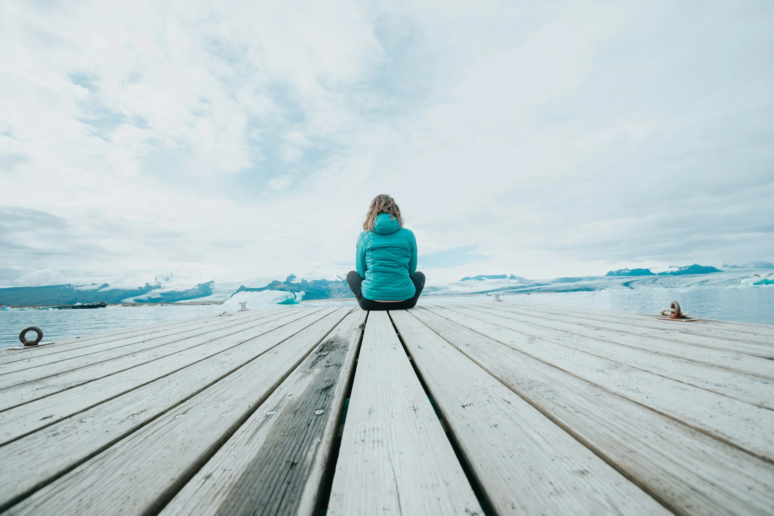 Mujer sentada en un muelle mirando el agua