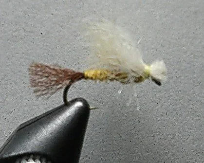Close-up of a fishing fly lure with gray and white feathers, attached to a fish hook.