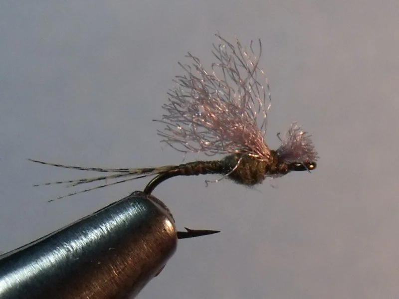 Close-up of a fishing hook with a dry fly fishing lure attached, set against a plain background.