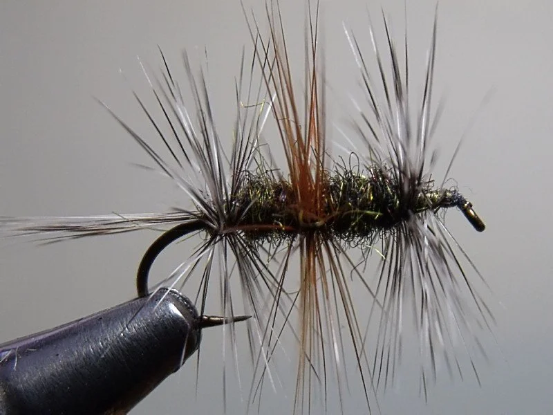 Close-up image of a fishing fly tied with thread and synthetic or natural materials, used as bait for fishing.