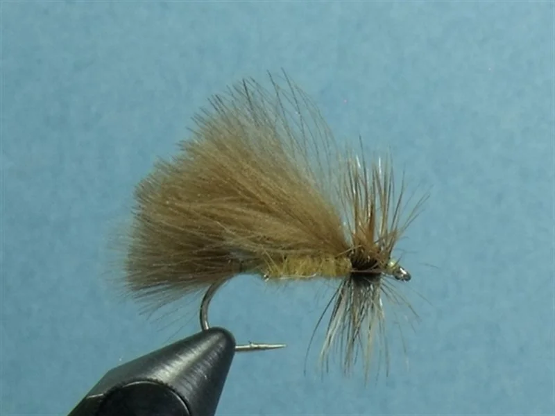 Close-up of a fishing fly with tan and brown feathers attached to a hook