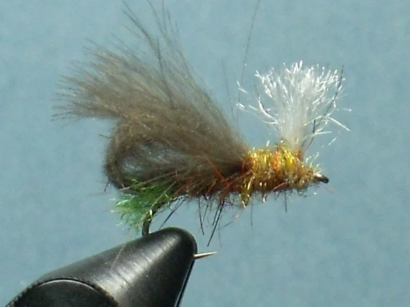 Close-up view of a fishing fly with brown, green, and white feathers mounted on a fishing hook.