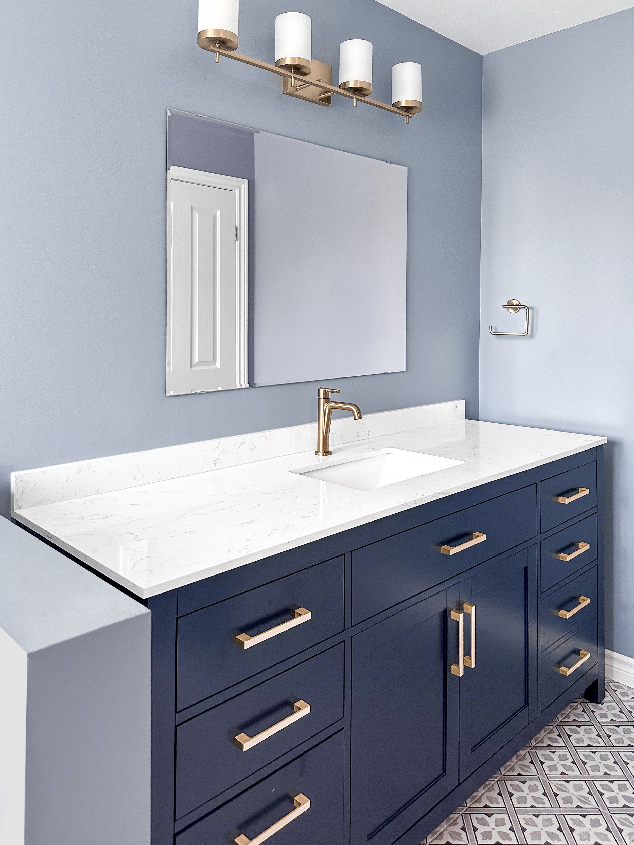 Primary ensuite bathroom renovation in Kitchener featuring a navy blue vanity, quartz countertops, and brushed gold lighting fixtures.