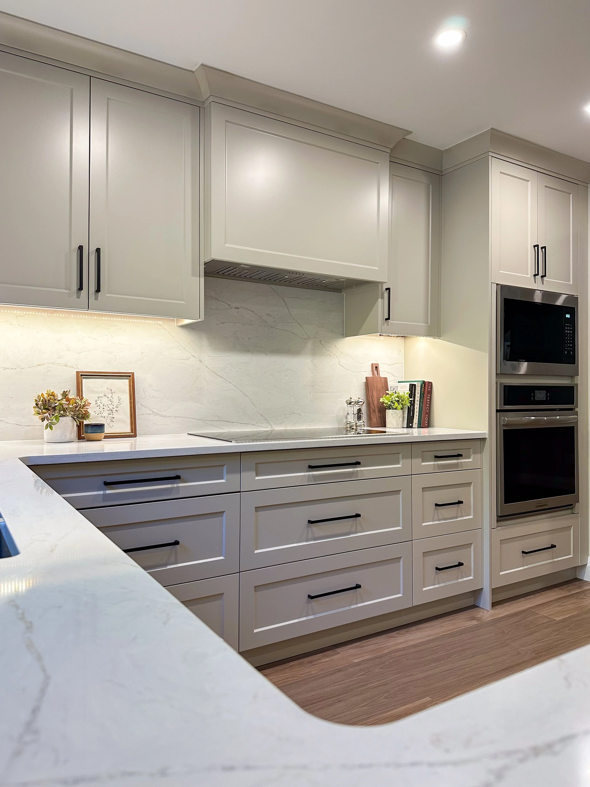 Warm Neutral Kitchen With Custom Hood Fan and Seamless Stone Backsplash