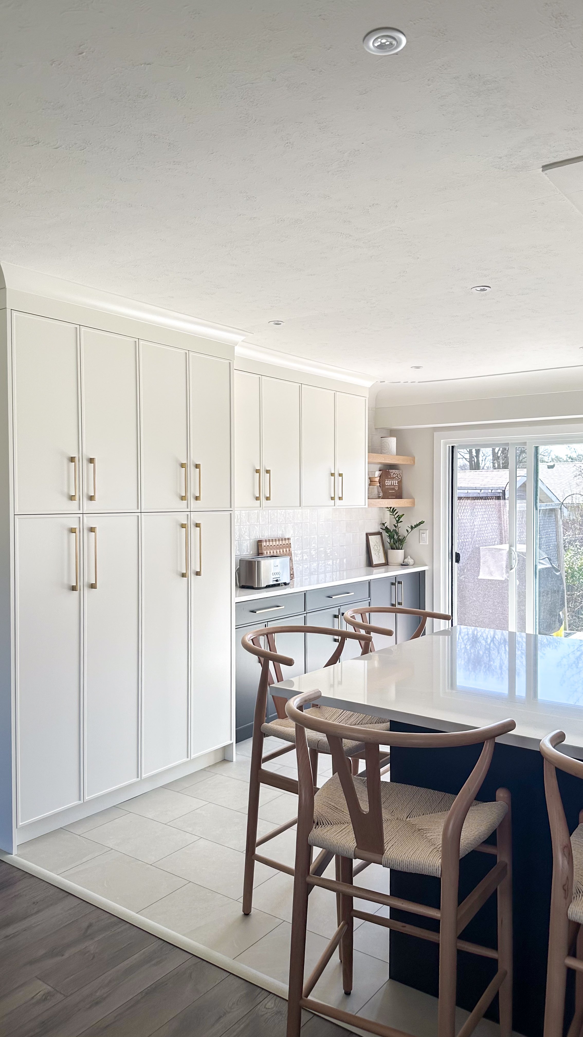 A look at the new floor-to-ceiling pantry wall, designed to maximize closed storage capacity. The warm white cabinetry and long brushed brass hardware keep the massive storage footprint feeling incredibly light and airy.