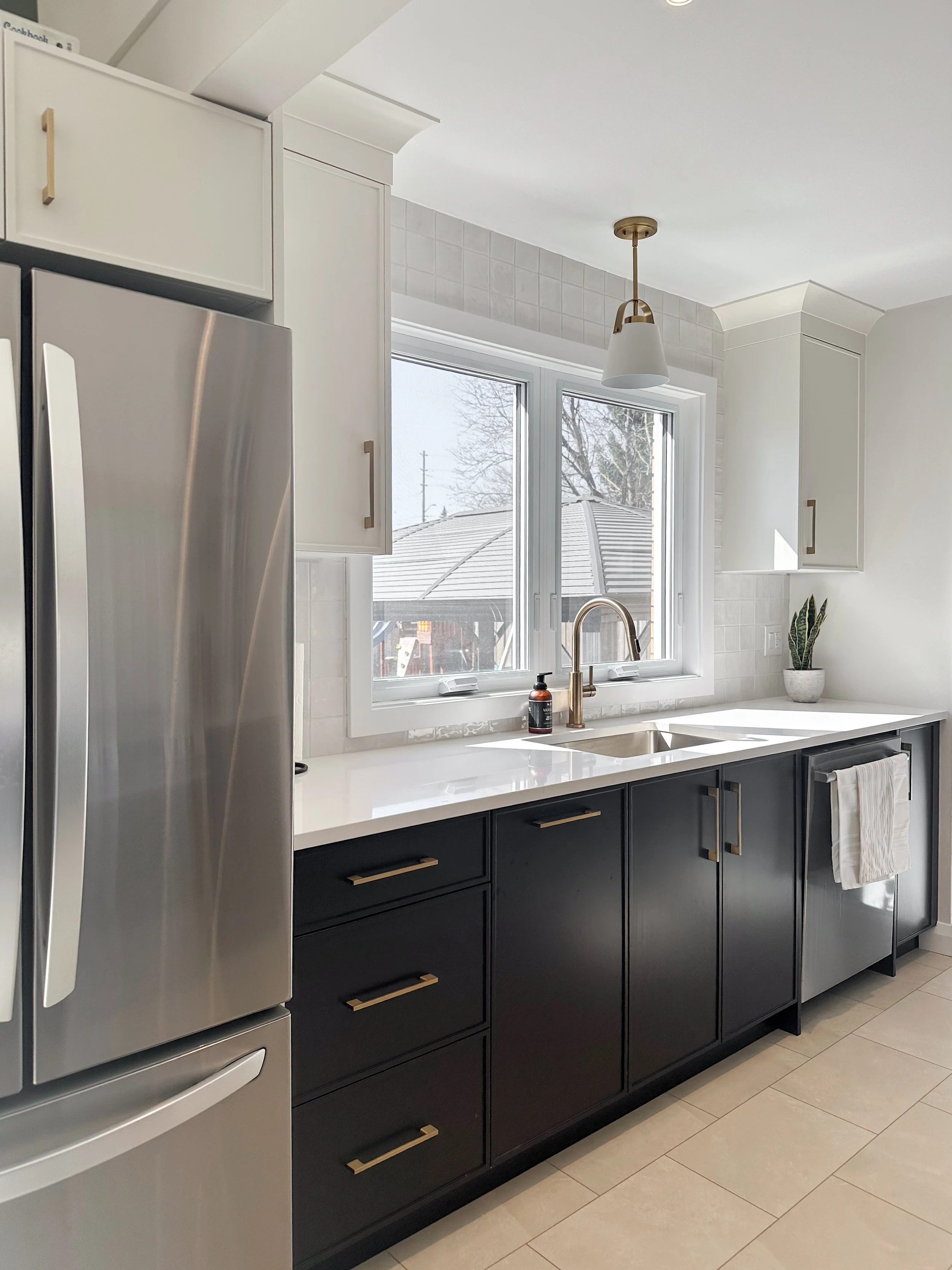 The cleanup zone is now flooded with natural light. By integrating the relocated fridge into this wall, we kept the main prep areas wide open. A sleek brushed brass faucet and white quartz countertops keep the space feeling crisp and clean.