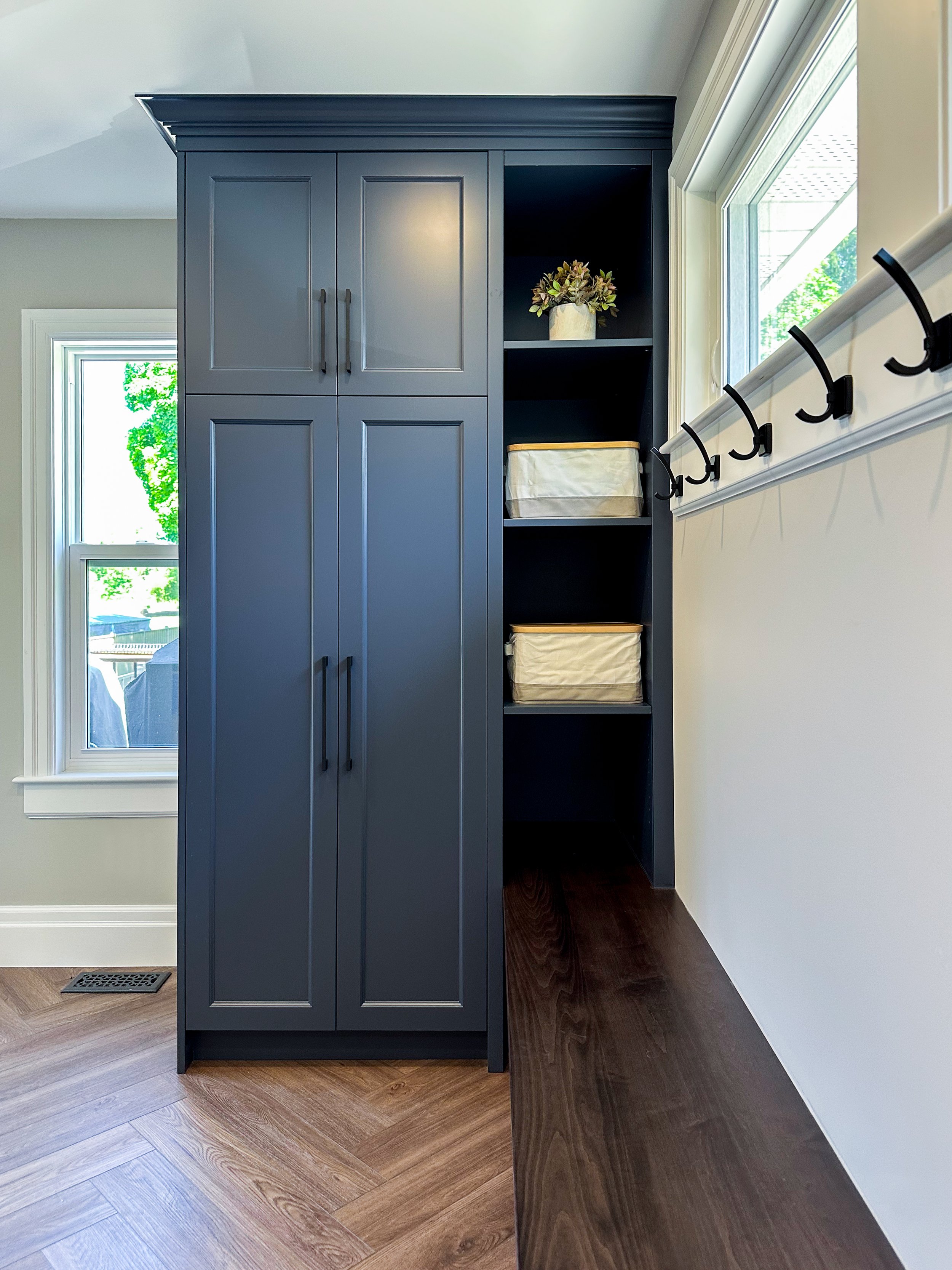 Custom entryway cabinetry in New Hamburg highlighting a tall built-in wardrobe and open storage cubbies for family organization.