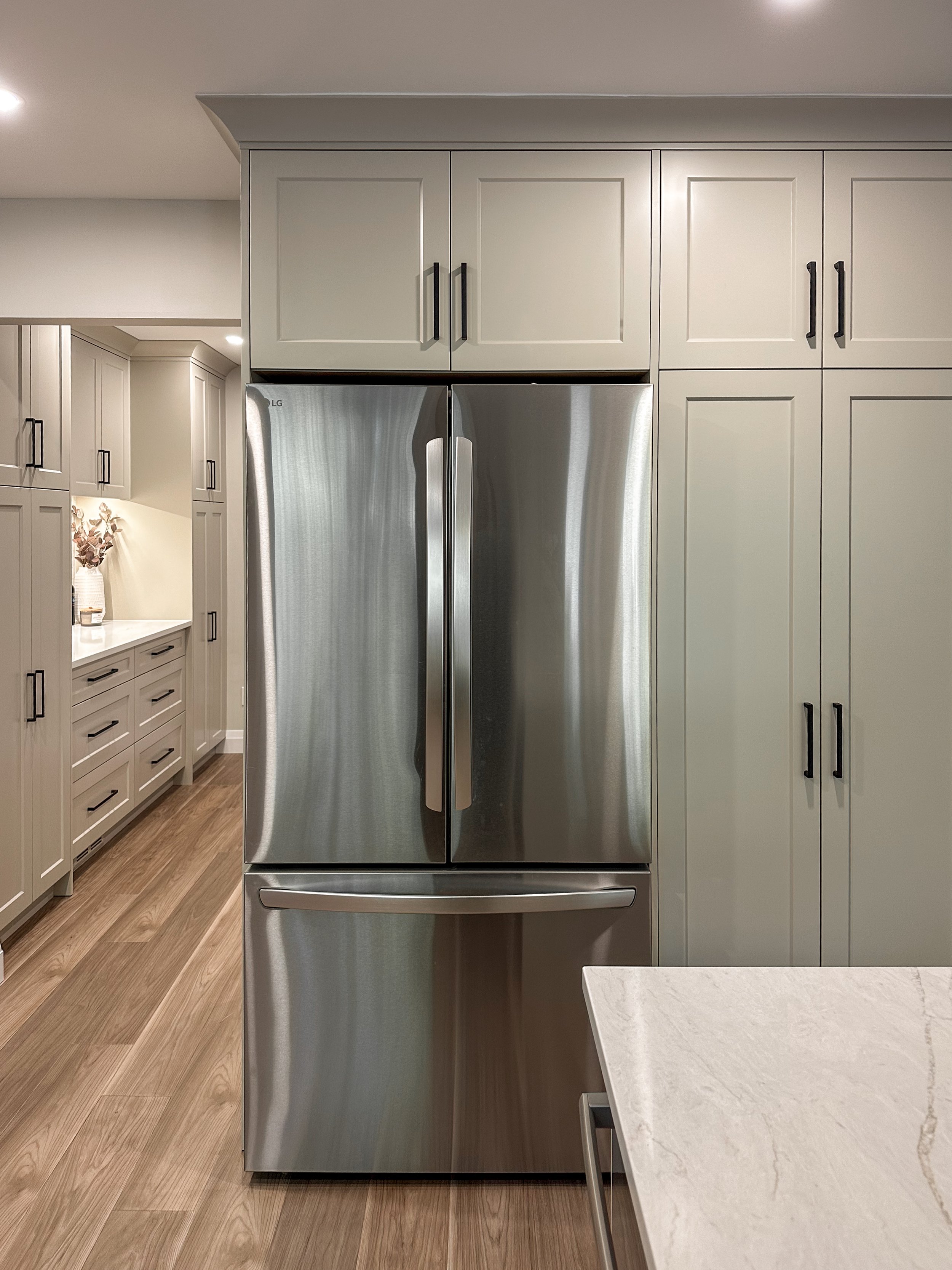 Built-In Refrigerator Surround With Tall Warm Grey Cabinetry and Vertical Storage
