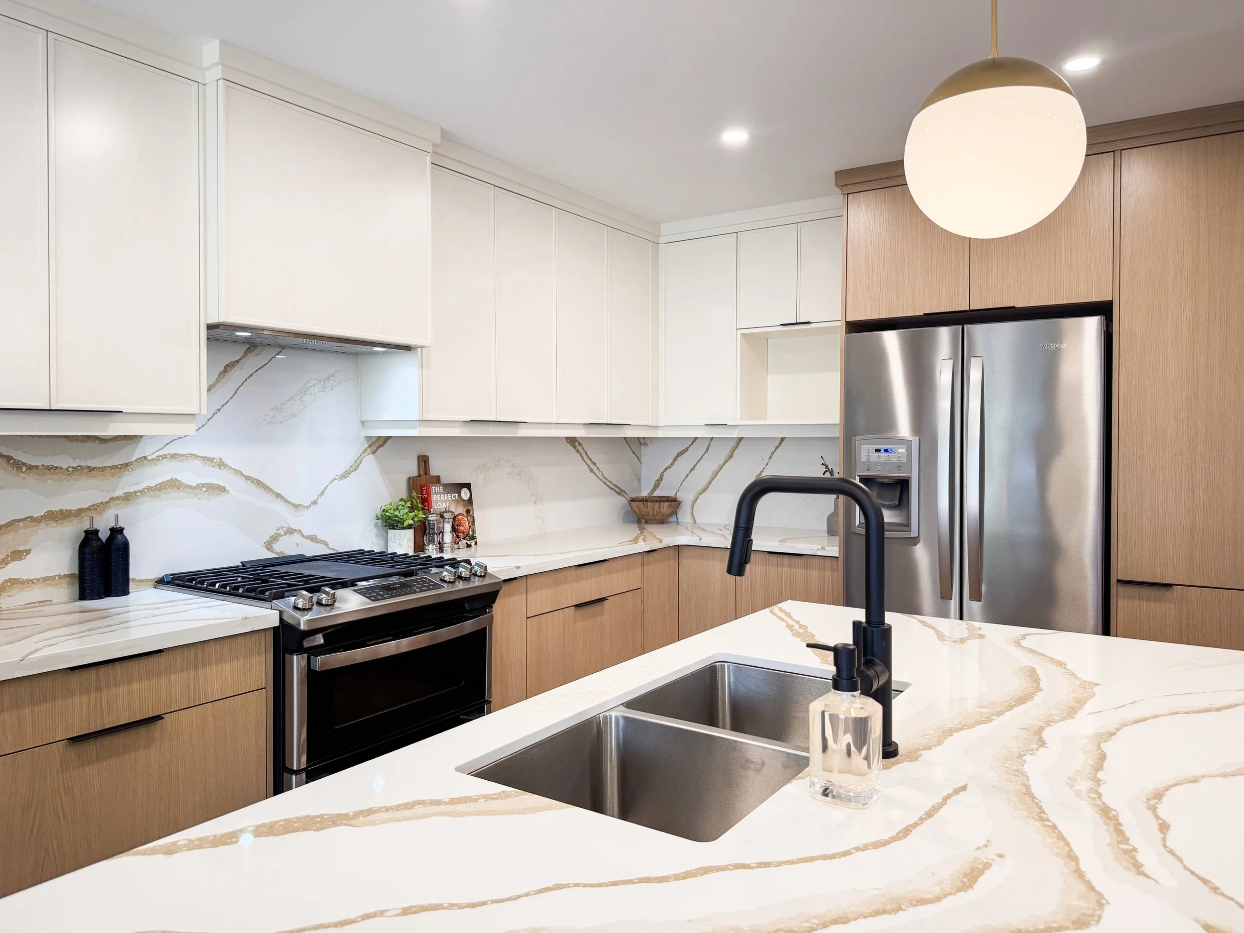 Complete Kitchen Renovation with Spacious Island, Ample Storage, Dual Tone Custom Cabinetry and Striking Continuous Backsplash and Countertops.
