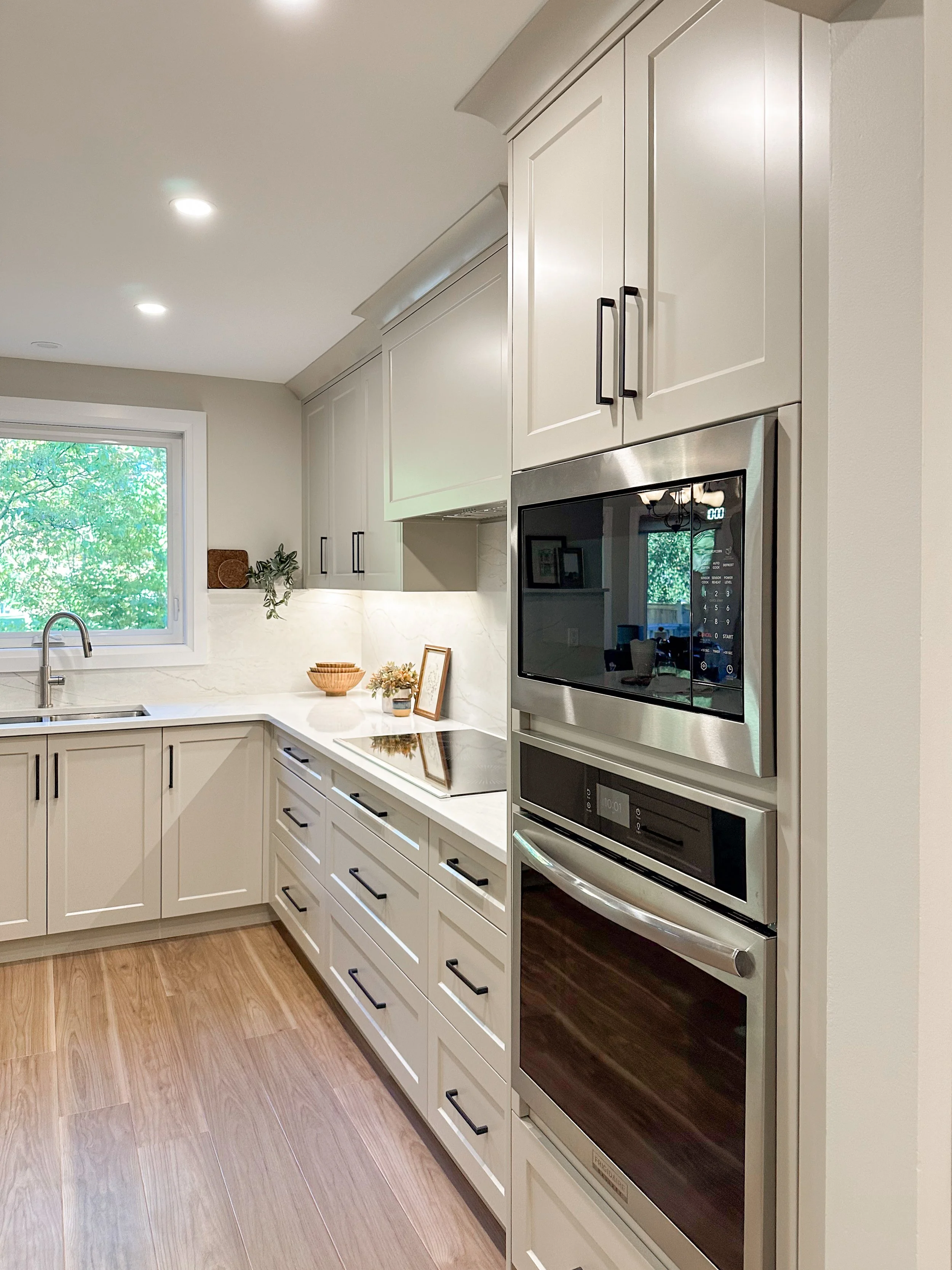 Spacious Kitchen Layout With Warm Wood Flooring and Neutral Shaker Cabinets