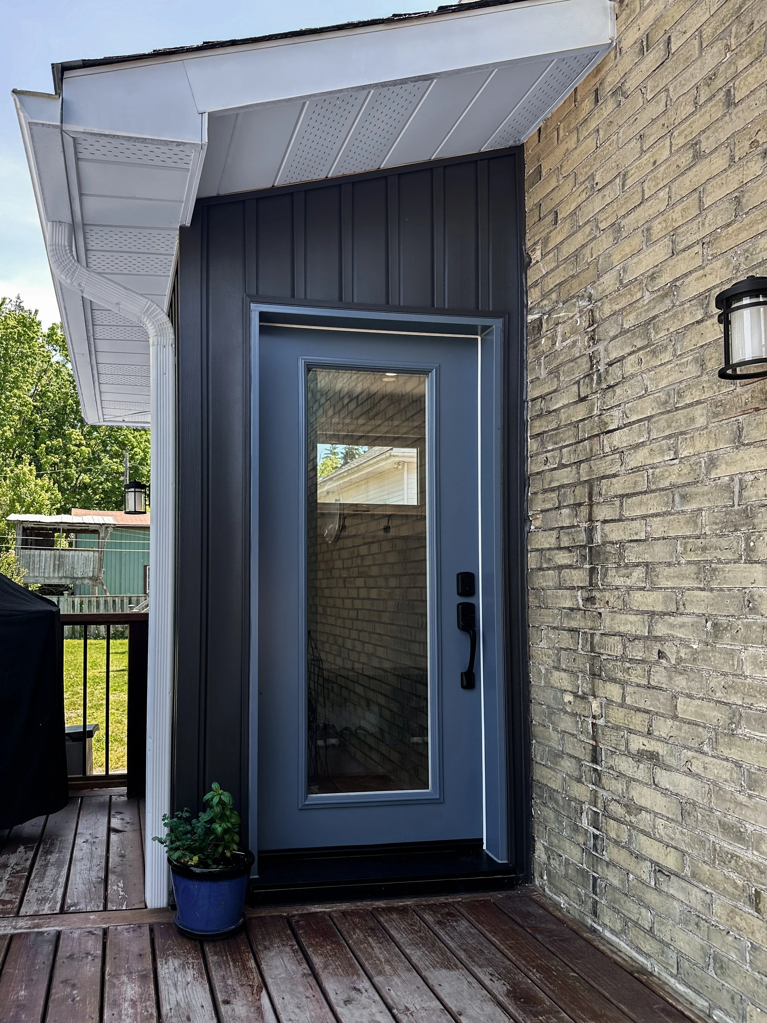 Mudroom exterior renovation in New Hamburg featuring a new glass-pane entry door and modern black hardware.