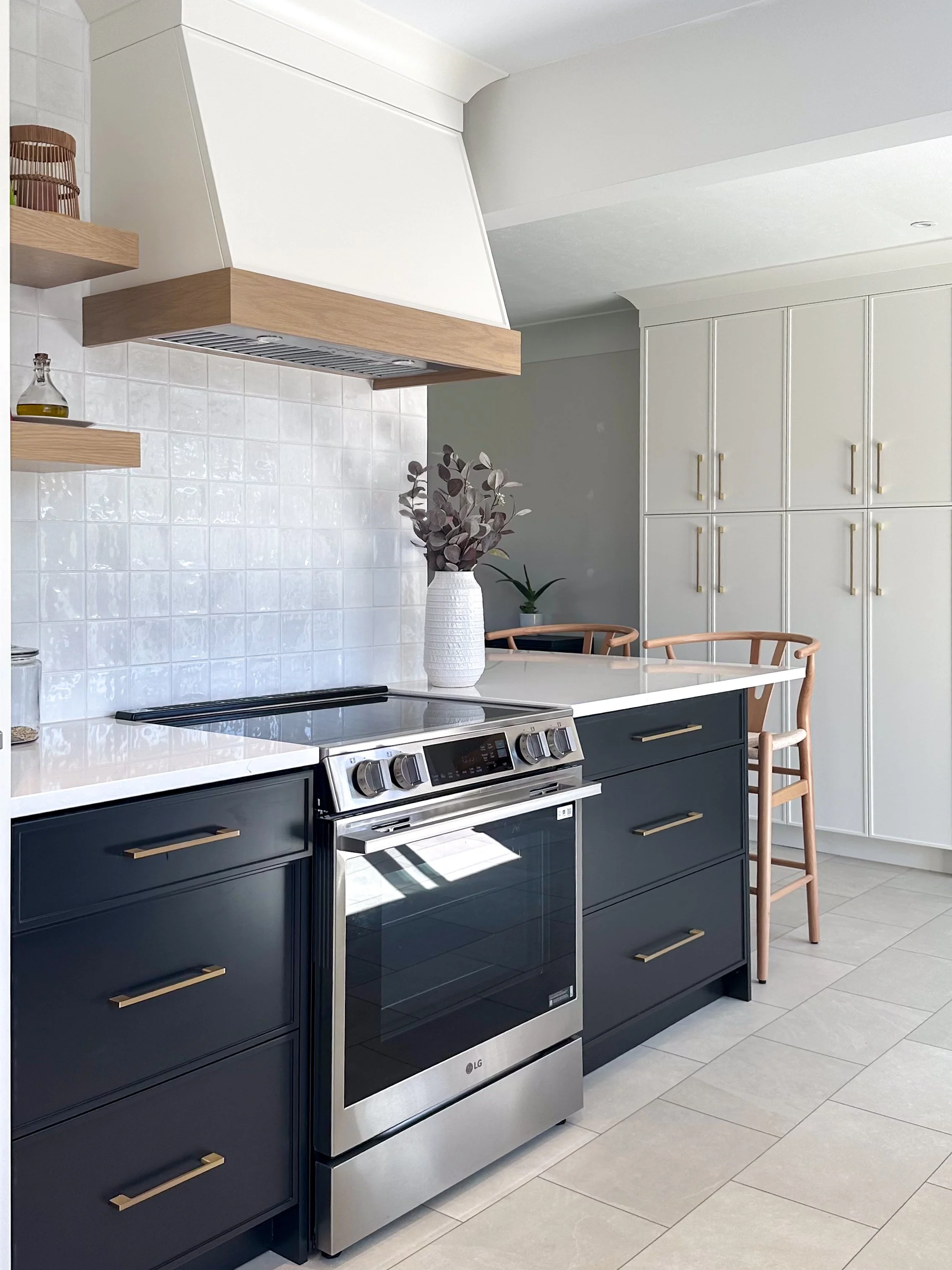 By cleaning up a dated mismatched peninsula, we were able to run a single, continuous white quartz countertop across the main island zone. Deep charcoal drawers ground the primary cooking station, offering a stark, beautiful contrast to the custom oa