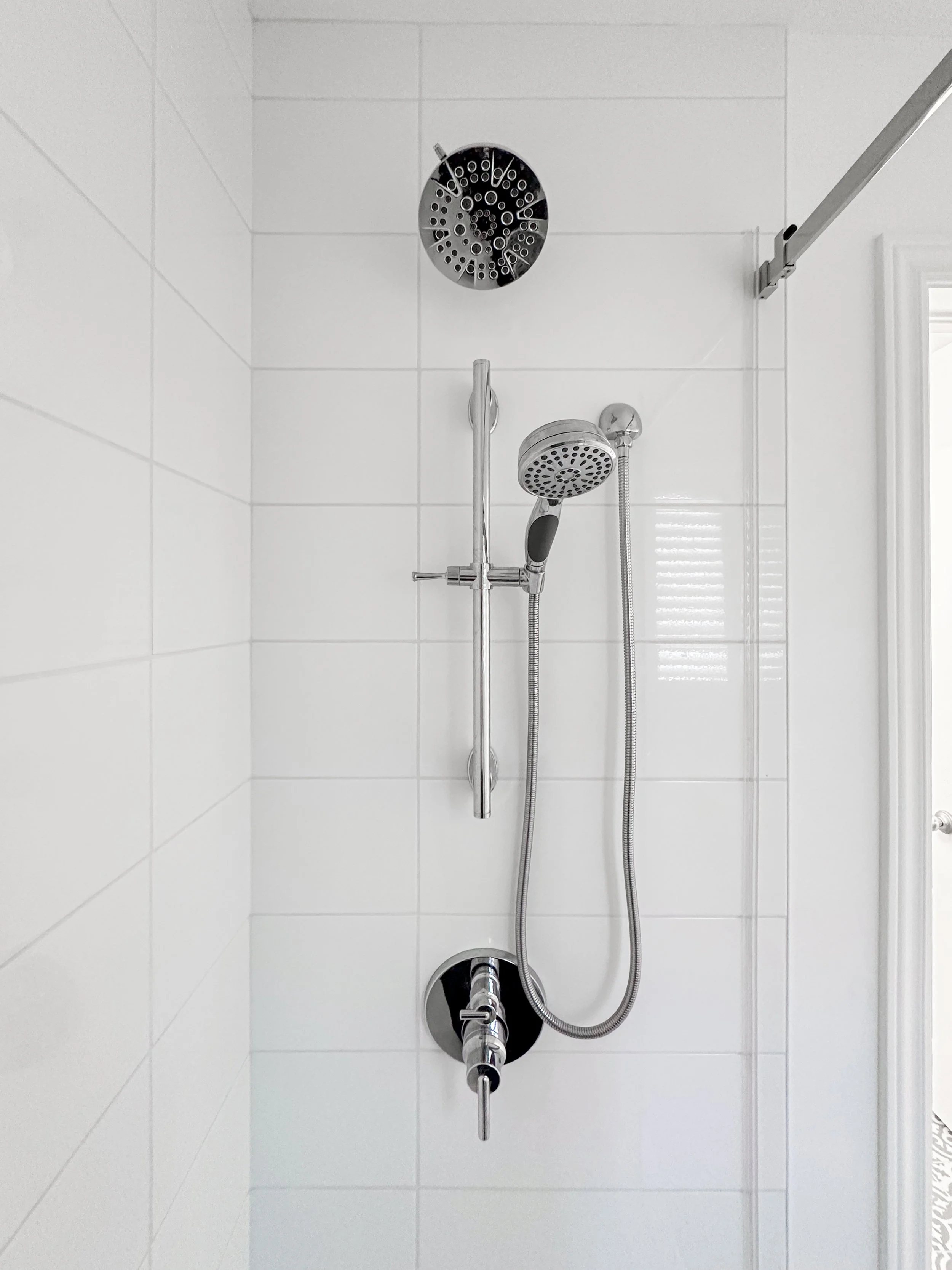 Bathroom shower renovation in Kitchener showcasing bright white tile and modern chrome shower hardware.