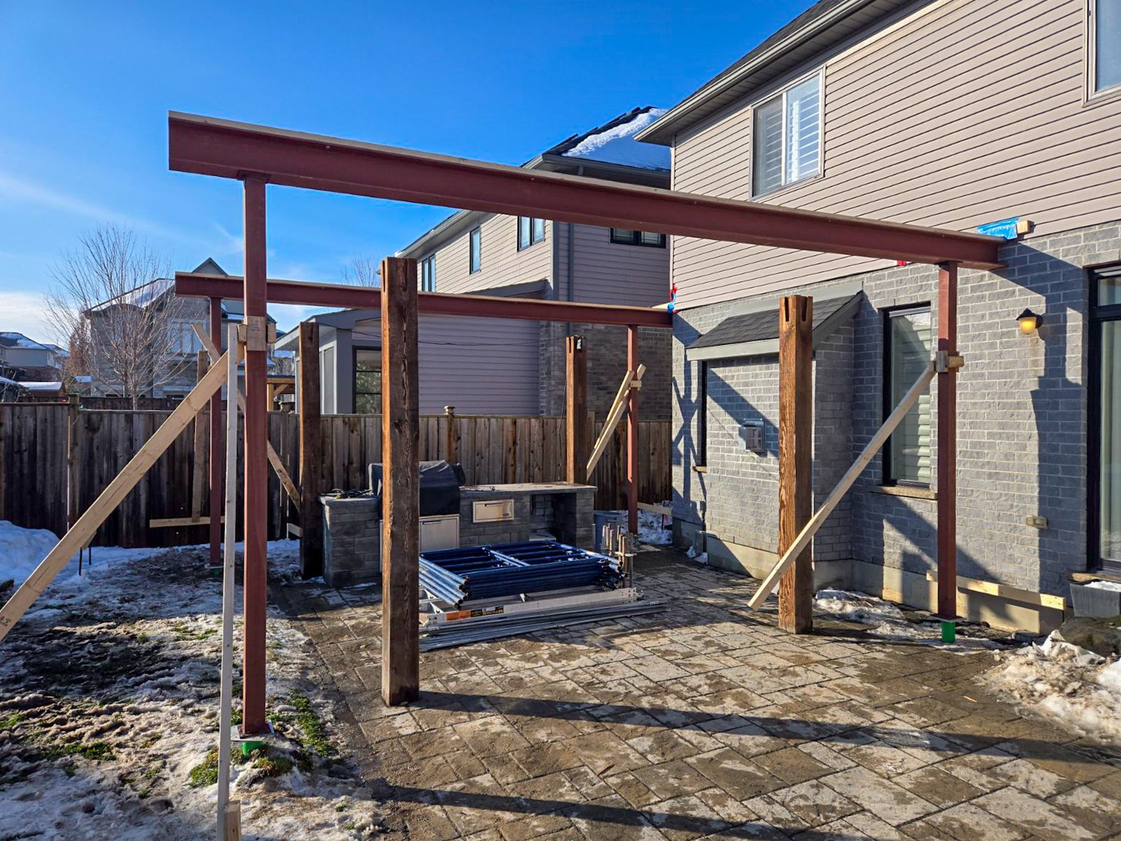 For the structural framing phase, heavy-duty steel I-beams and support posts were built directly over the existing hardscape to safely support the weight of the new addition.   