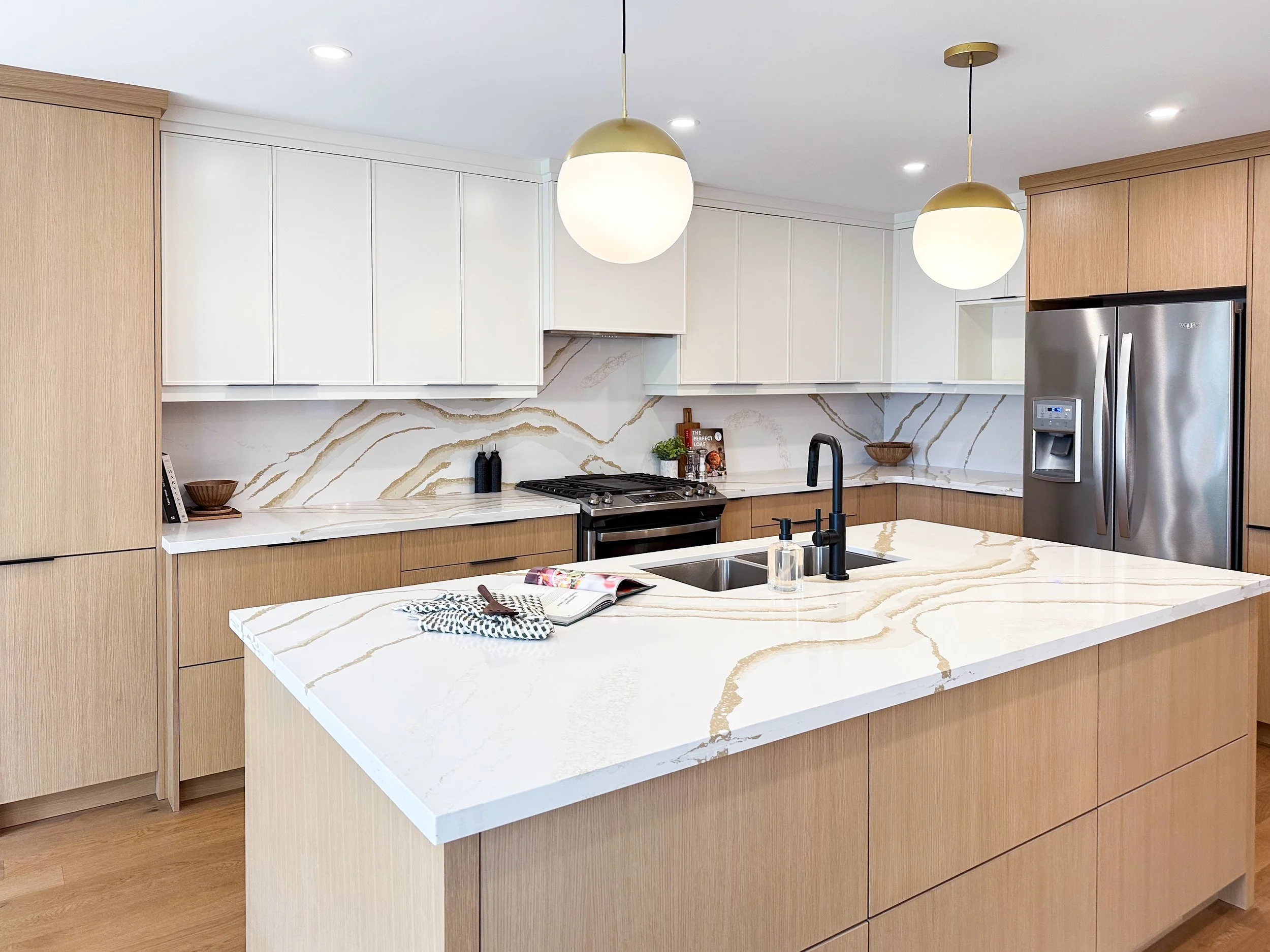 Complete Kitchen Renovation with Spacious Island, Ample Storage, Dual Tone Custom Cabinetry and Striking Continuous Backsplash and Countertops.