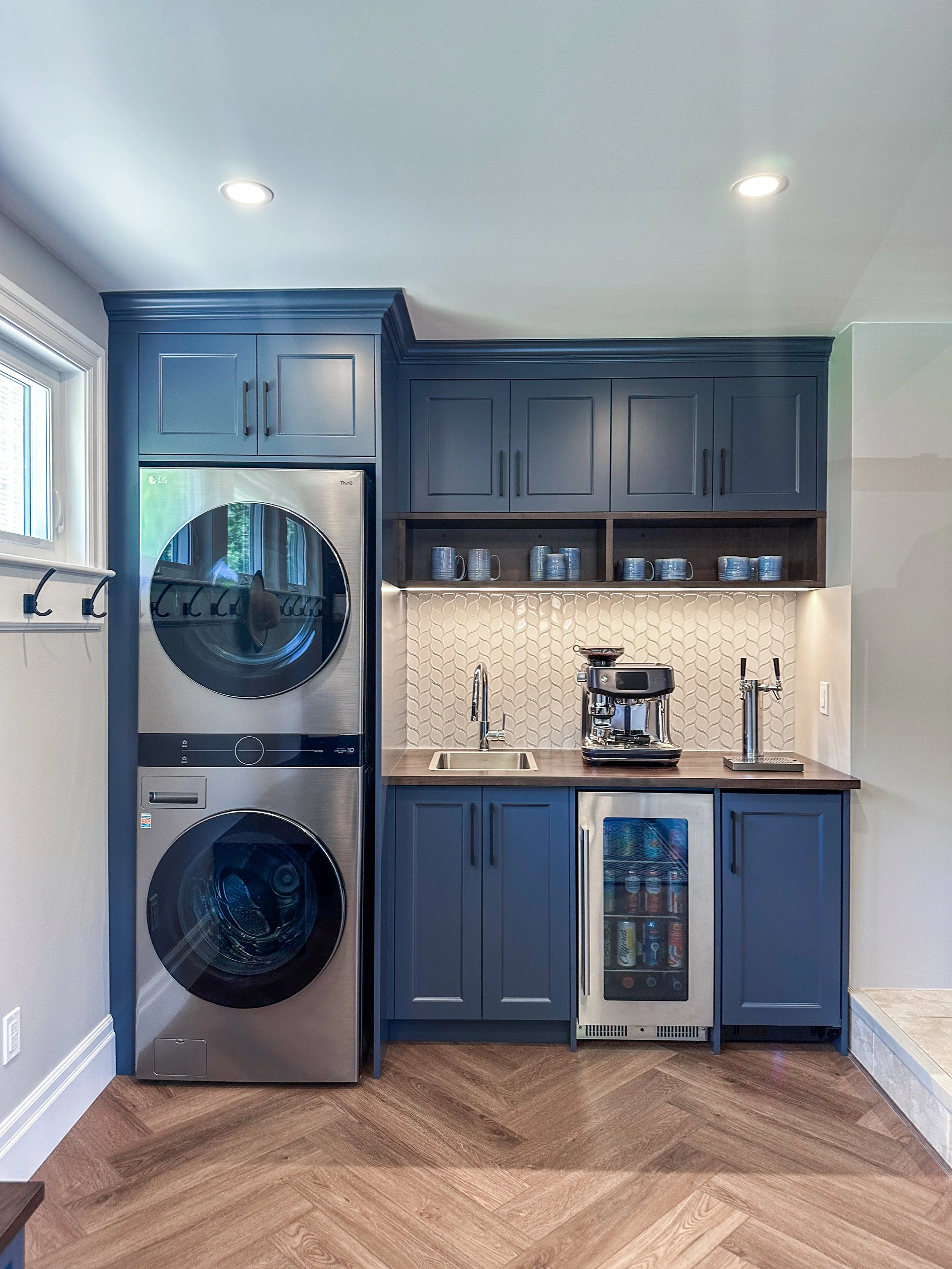 Luxury laundry and mudroom remodel in New Hamburg showcasing a custom home draft tap, stacked appliances, and a textured tile backsplash.