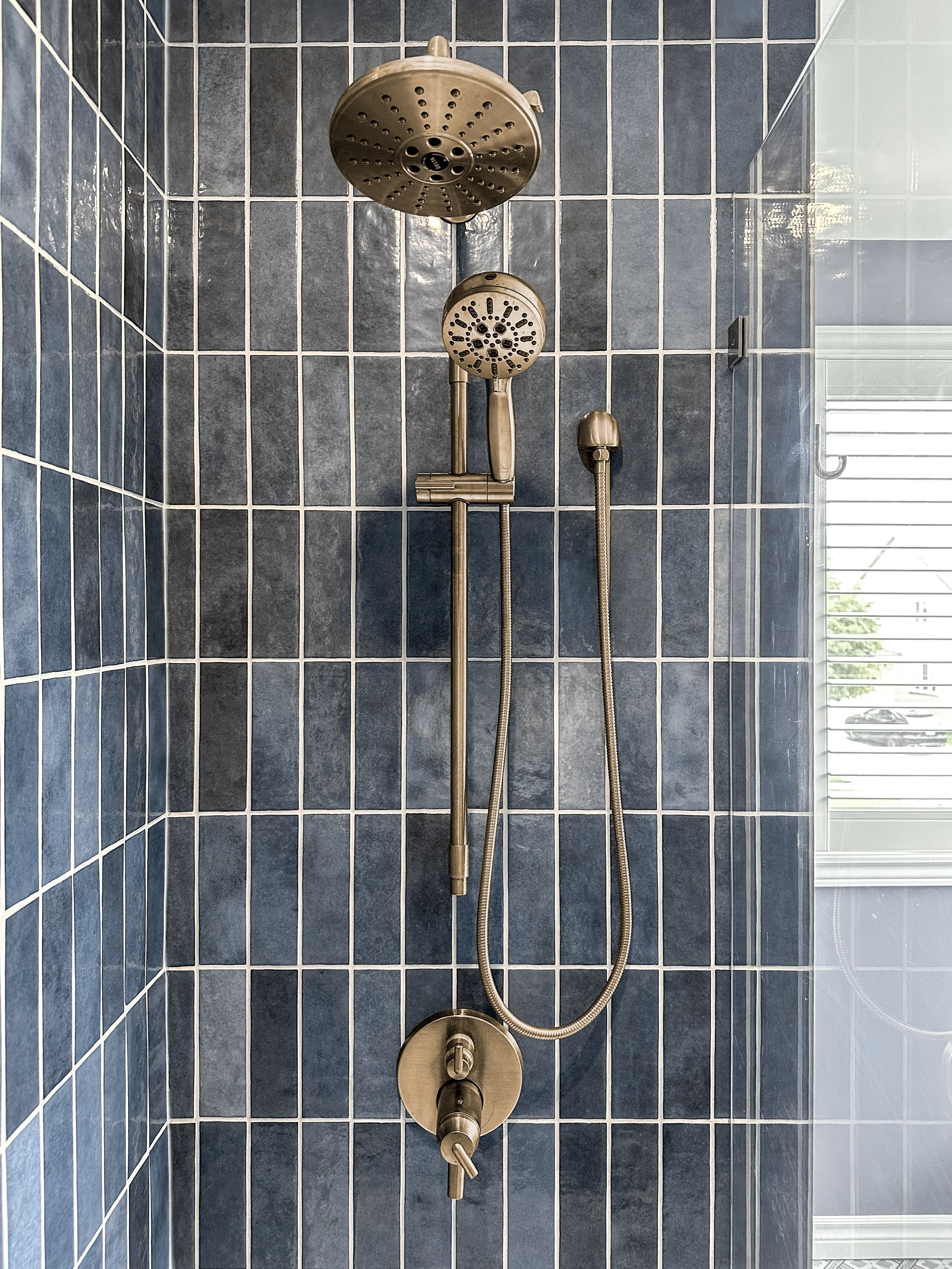 Luxury shower remodel in Kitchener featuring brushed gold shower fixtures against deep blue vertical tile.