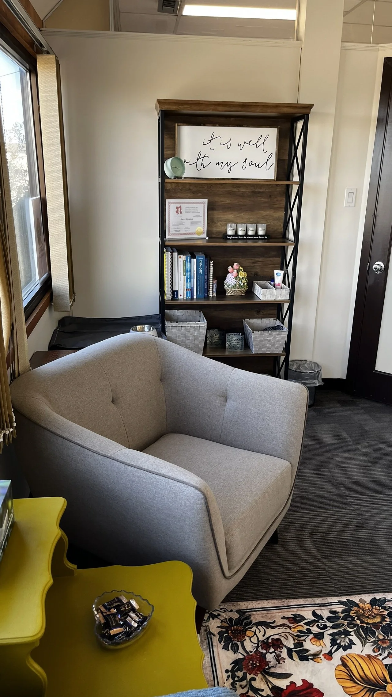 The side table with chocolates, big chair and bookshelf.
