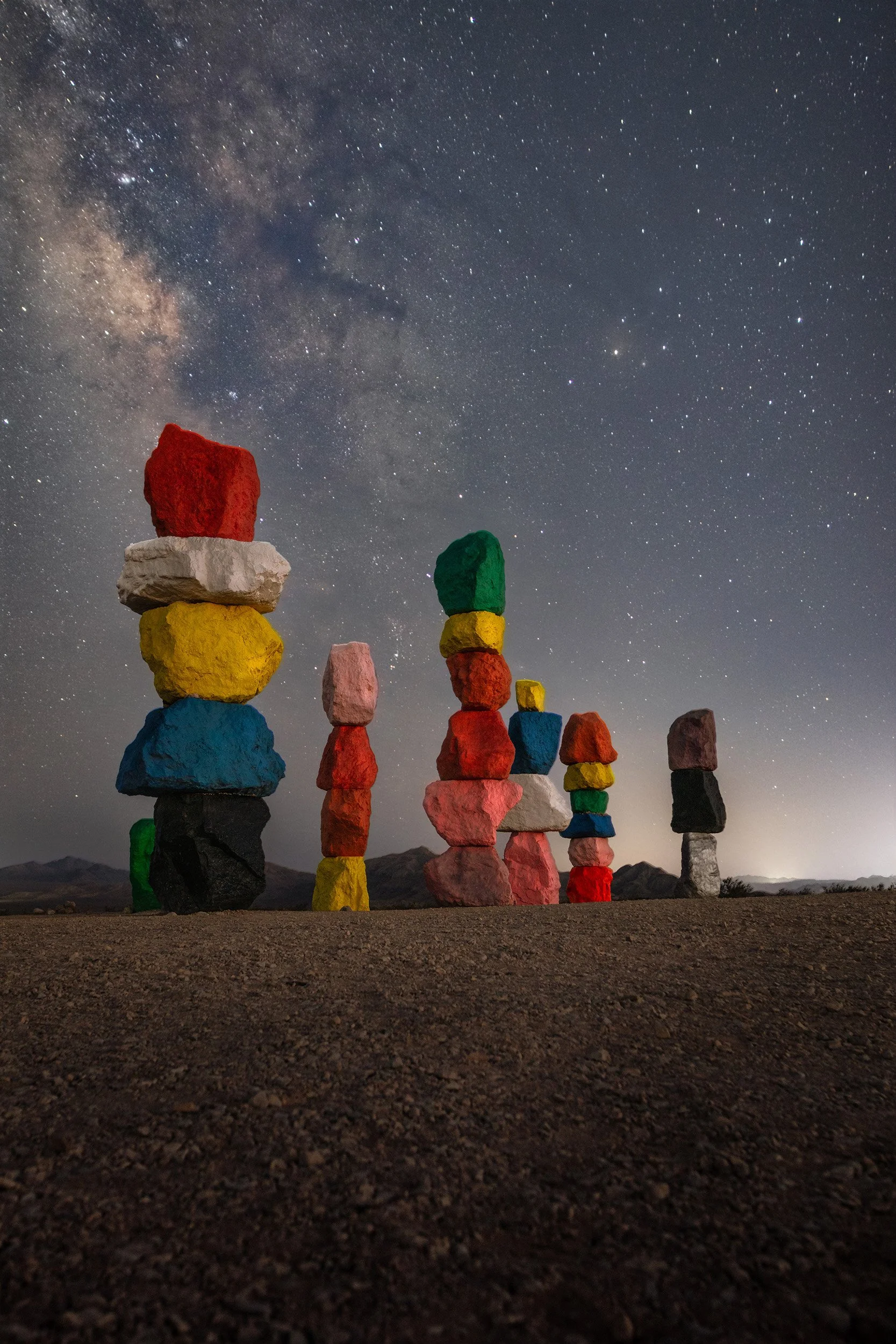 Colorful stacked rock formations under a starry night sky with the Milky Way galaxy visible