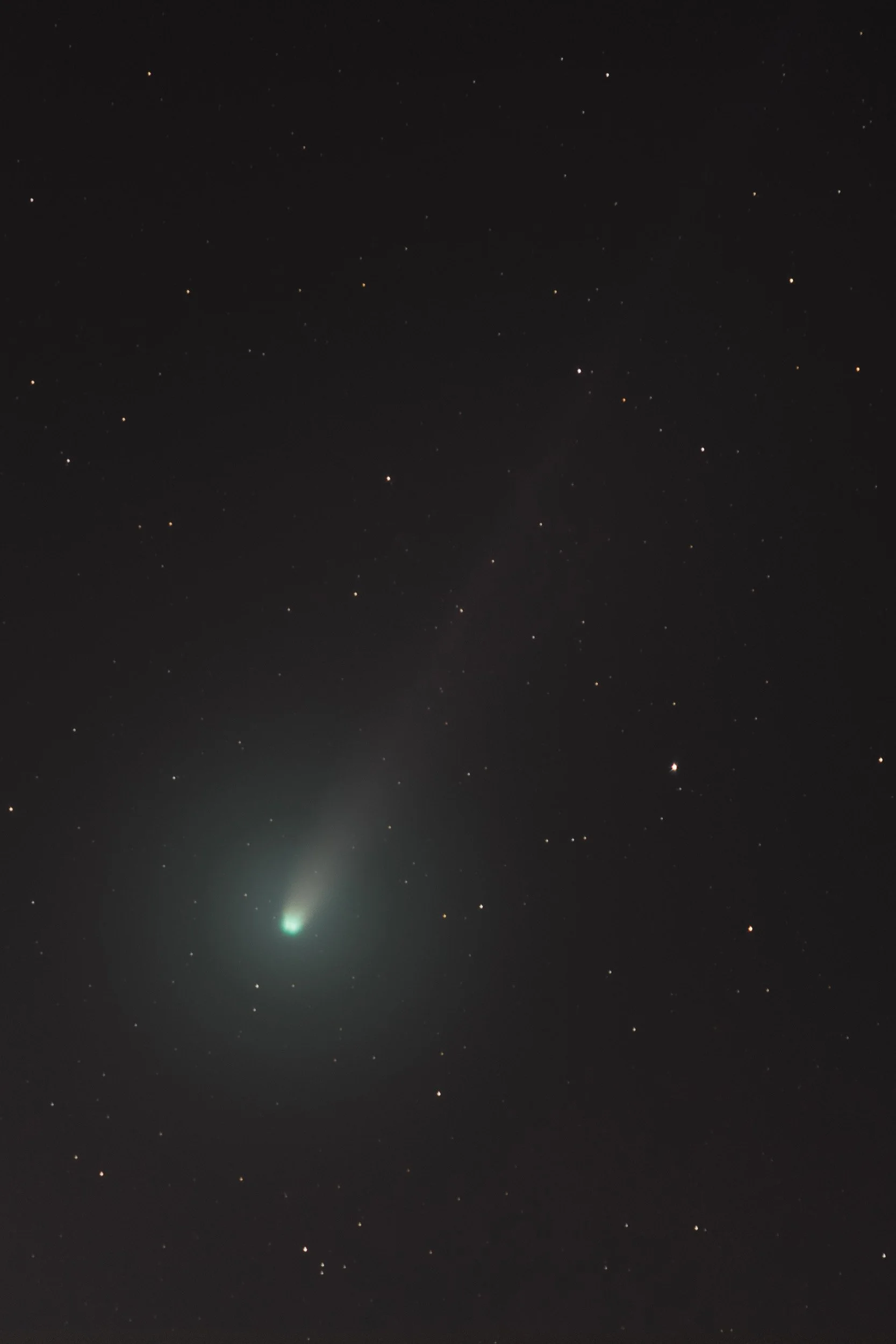 A photograph of a night sky with stars and a bright comet visible near the bottom left.