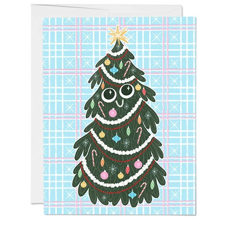 A Christmas greeting card featuring a cartoon Christmas tree with a smiling face, decorated with colorful ornaments, candy canes, and garlands against a light blue plaid background.