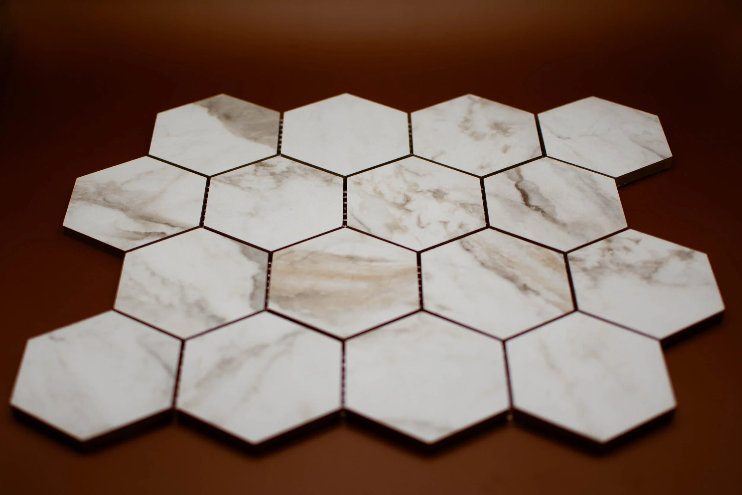 White hexagon marble tiles arranged on a brown surface.