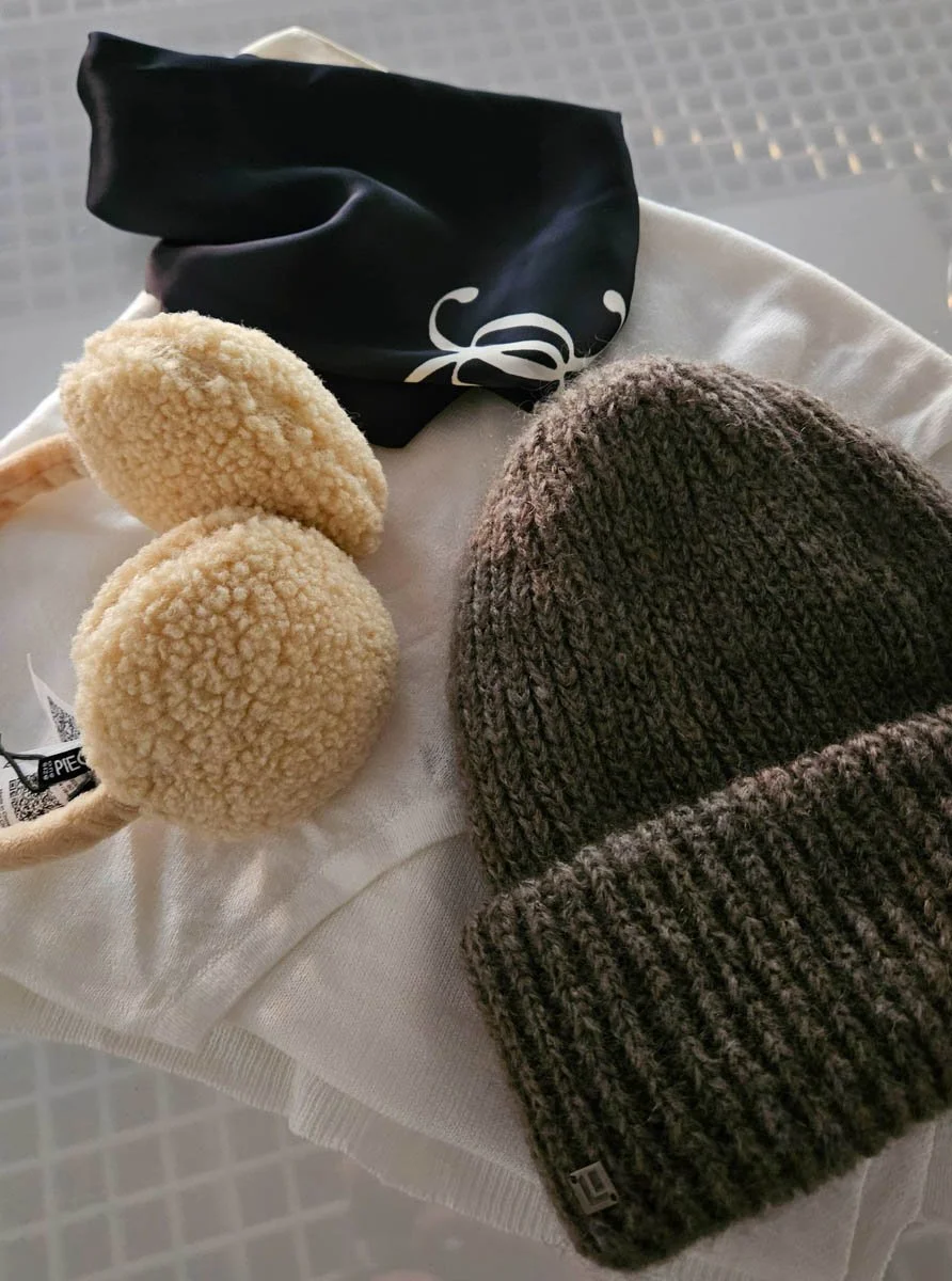 Mustat ja beiget talvihanskat tai pipot, toinen on kashmirkasvainen pipo ja toinen fleece-hattutyyppi, sekä musta ja valkoinen pyyhkeen tai hupun teippi.