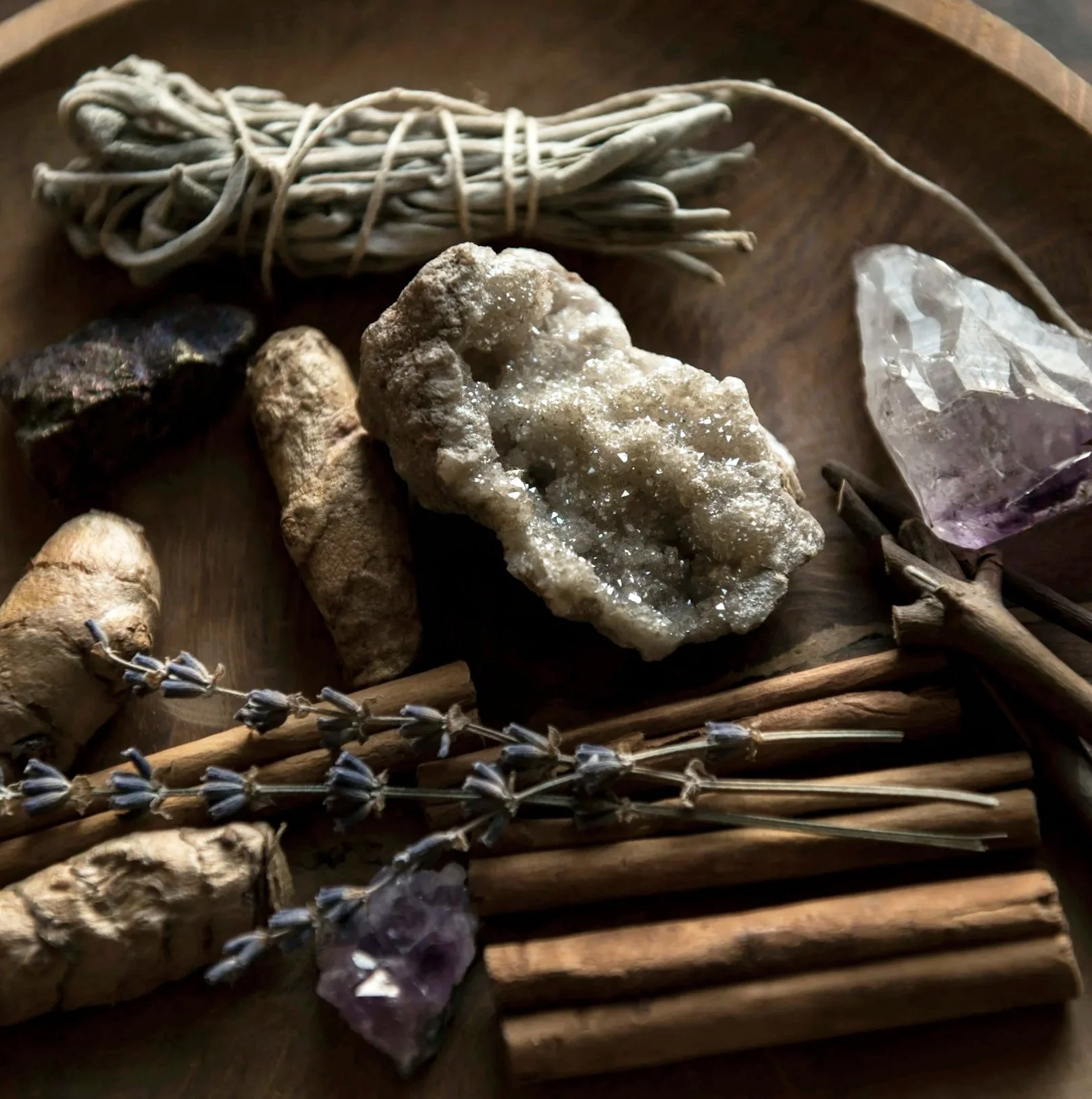 Collection of various crystals, dried lavender, and herbs displayed on a wooden tray.