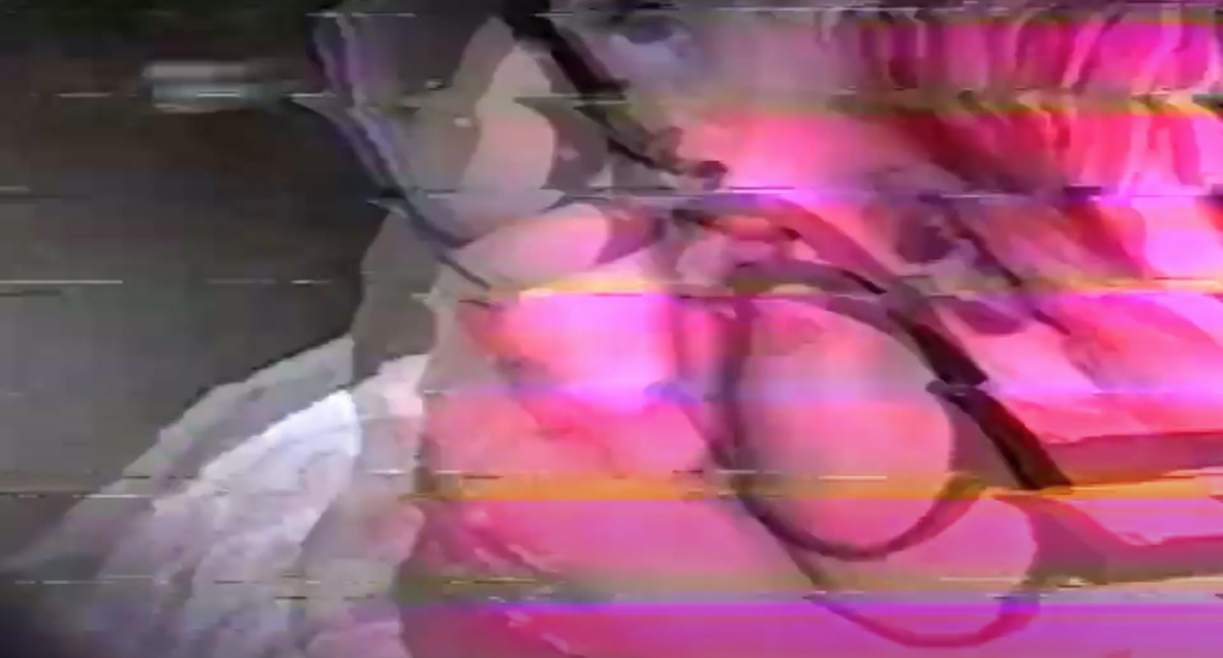 The image of a girl wearing glasses is distorted by VHS rewinding. Her face is filled with pink light
