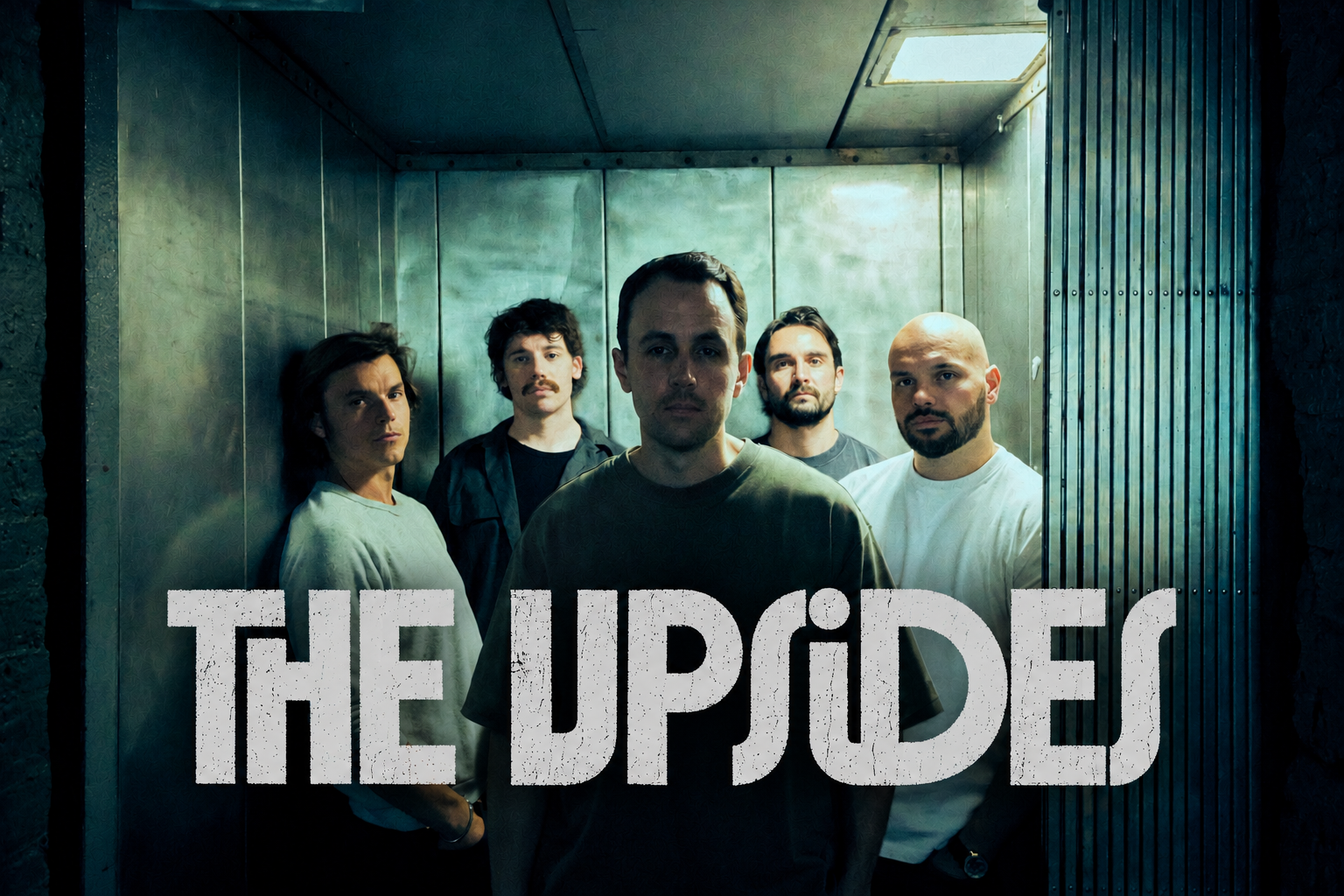 A band called 'The Upsides' with five members standing in an elevator. The members include five men, all looking at the camera with serious expressions.