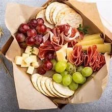 Charcuterie board with grapes, cheese, sliced bread, and cured meats