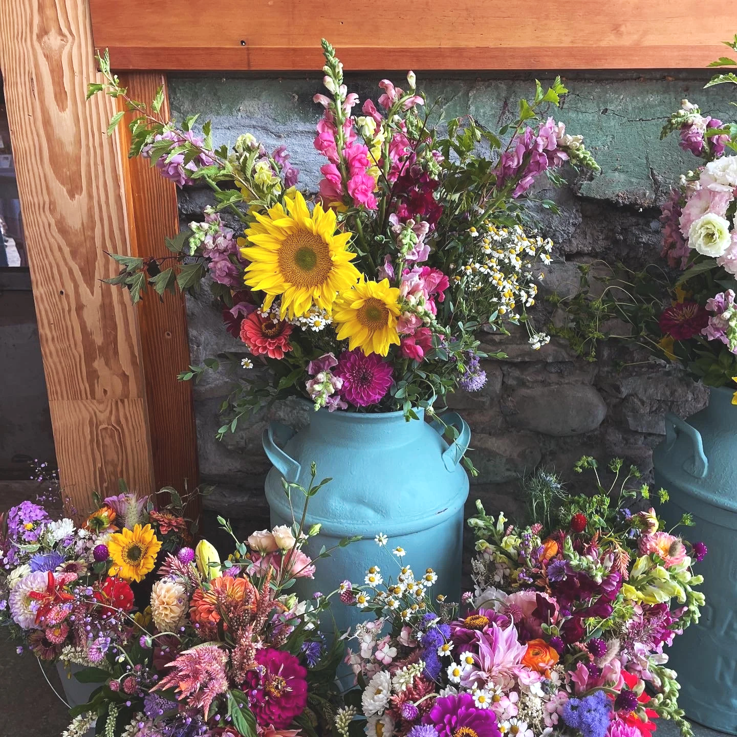 Colorful floral arrangements in vases with a brick and wooden background.