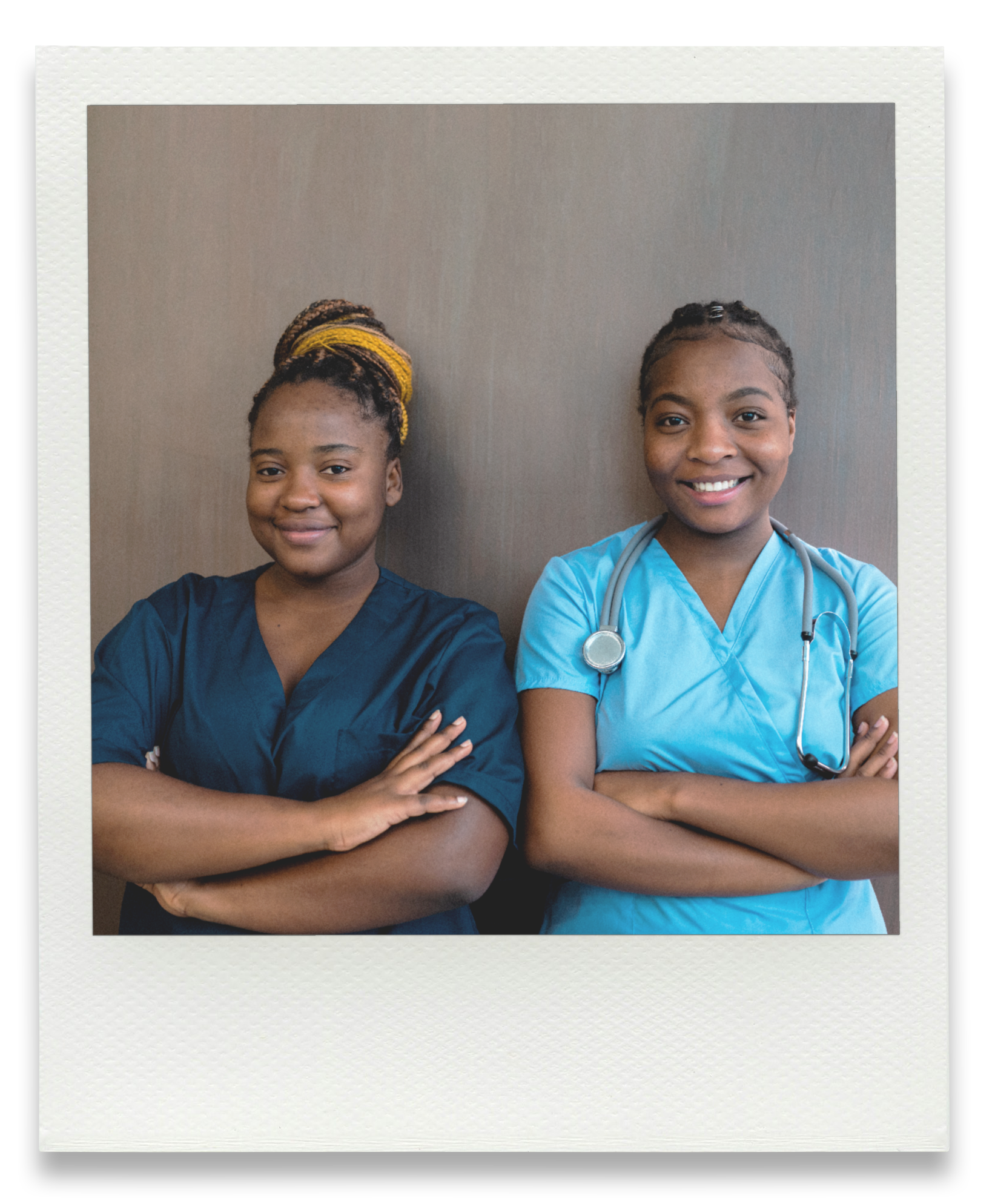 Two smiling female healthcare professionals with crossed arms, standing against a neutral wall. One wears dark scrubs with a yellow headwrap, the other in light blue scrubs with a stethoscope.