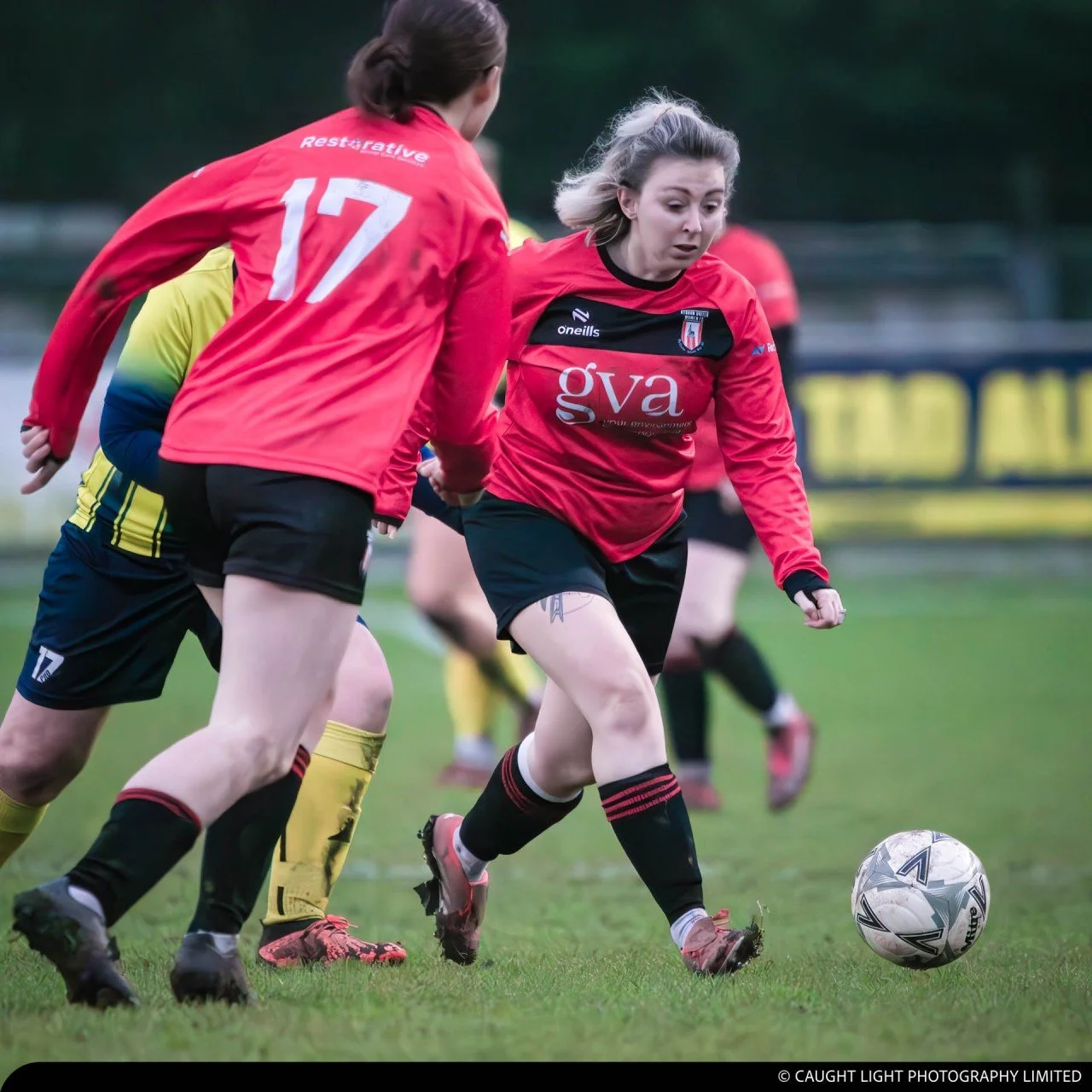 Cassie Marns, Founder of Marns Marketing, dribbling a football whilst wearing a Ryburn United red jersey and black shorts.