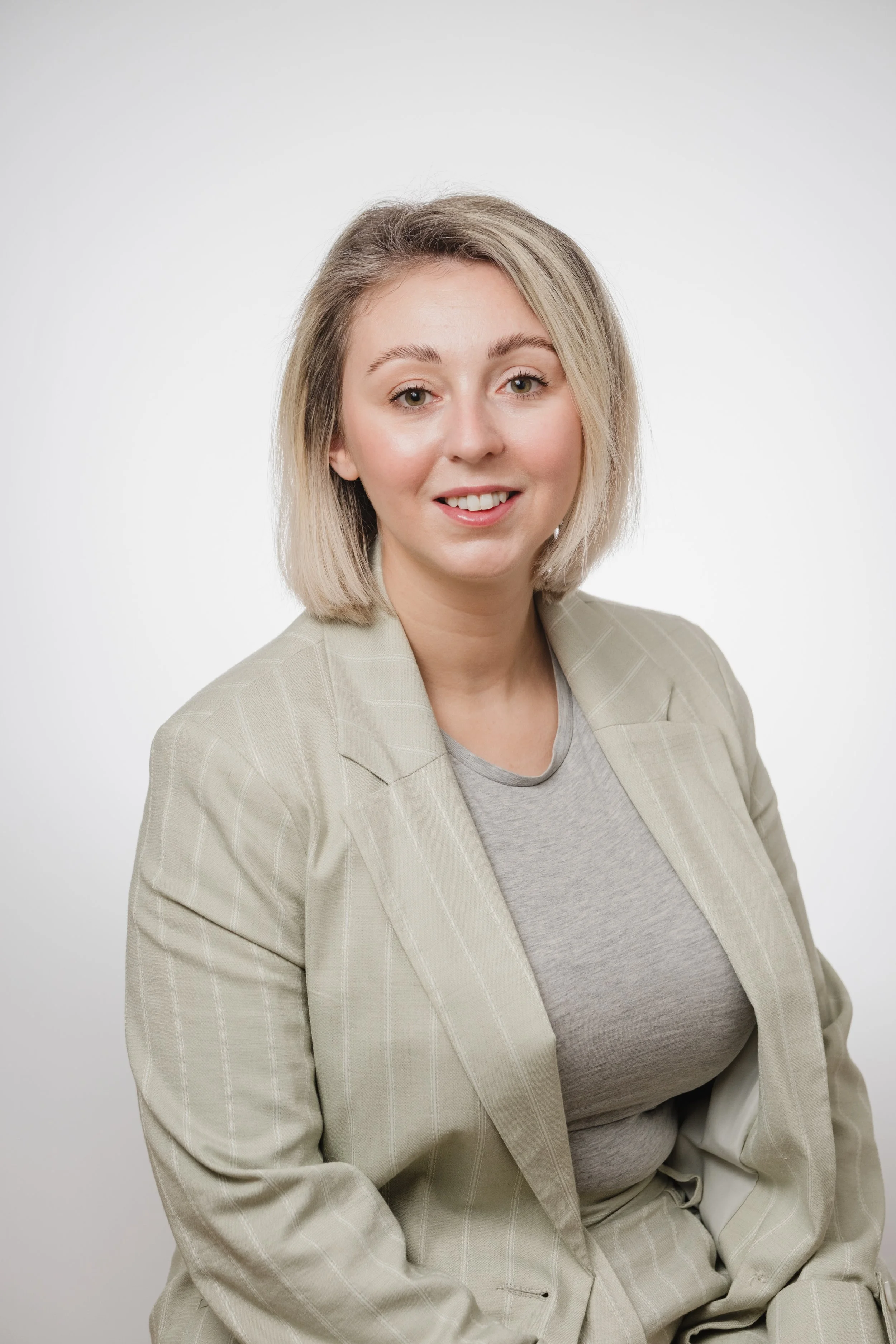 Cassie Marns, Founder of Marns Marketing wearing a beige blazer and gray shirt, smiling at the camera against a plain white background.