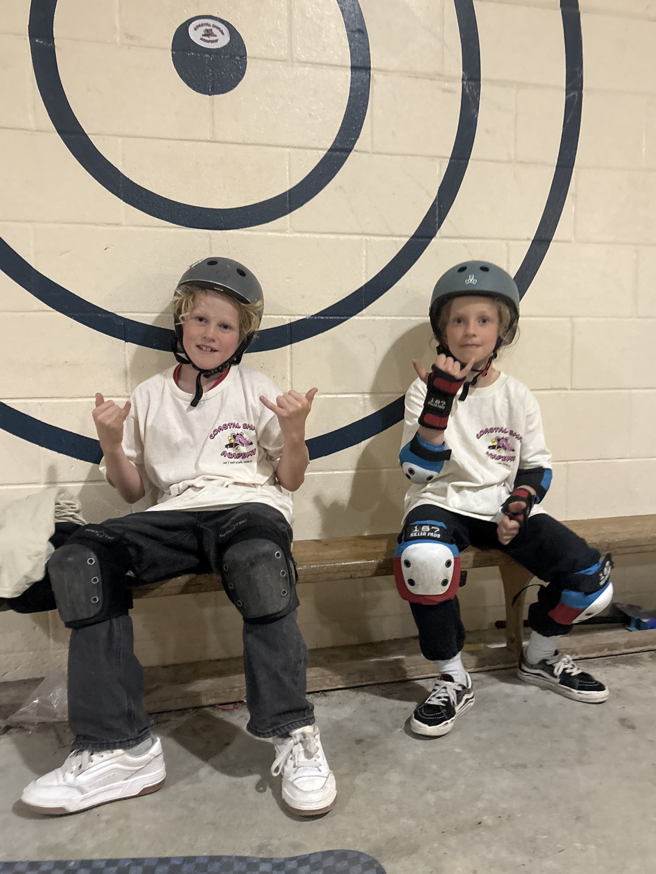 two young kids having skateboard lessons in tofino at the skatepark wearing coastal shred academy merch