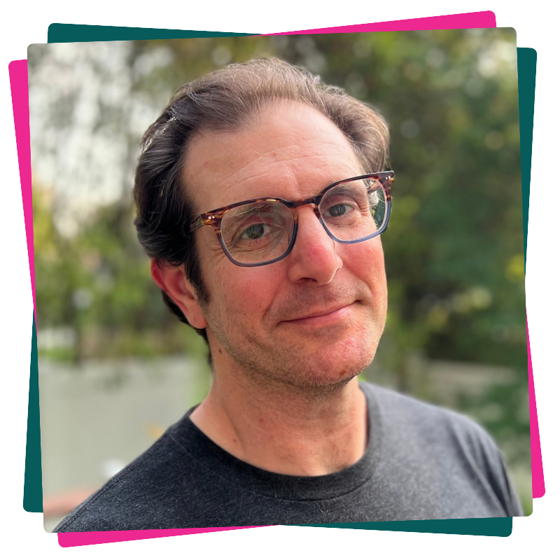 Headshot of Dan Brown. He wears a grey t-shirt and glasses. 