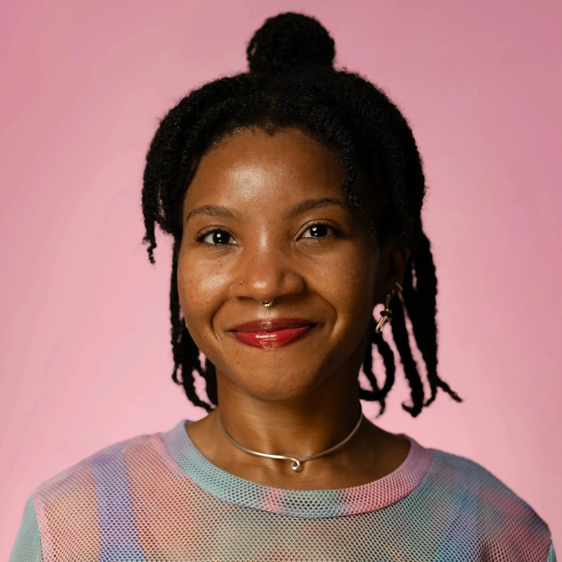 Headshot of Catt Small, a Black woman with shoulder-length braids wearing a pink and blue top.