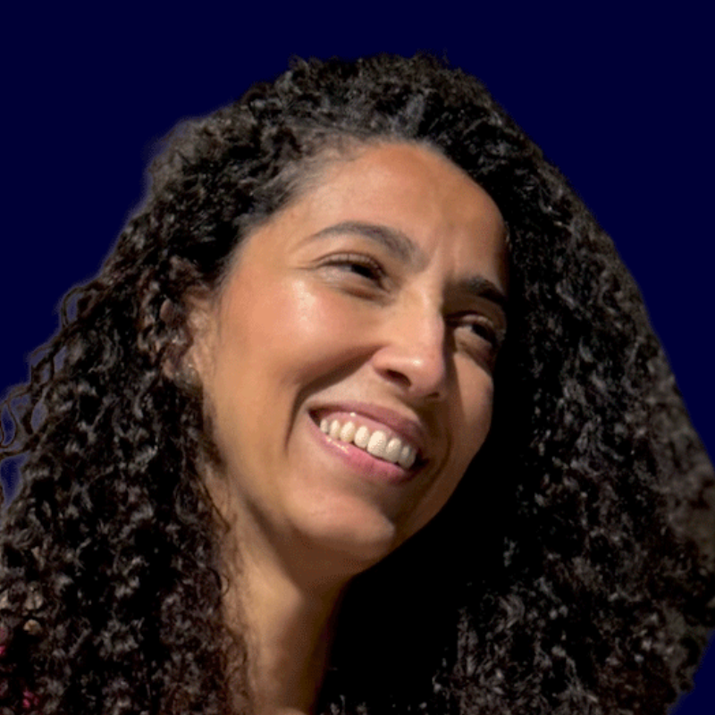 Headshot of Jasmine Ibrahim. She is a brown-skinned woman with curly dark hair and looks to the side.