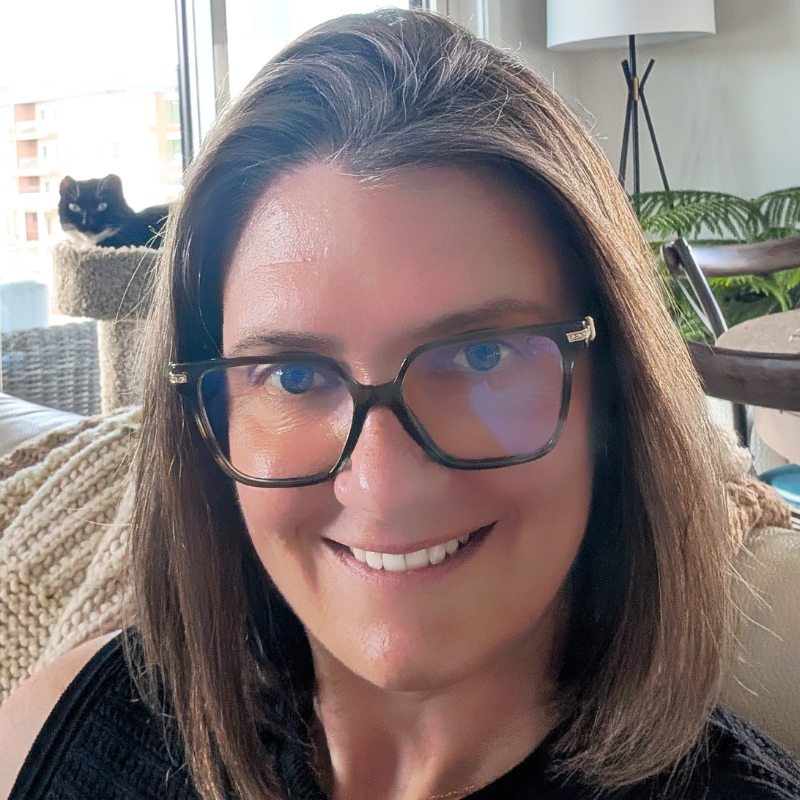 Headshot of Adriana Harper, a woman with shoulder-length dark blond hair and glasses.