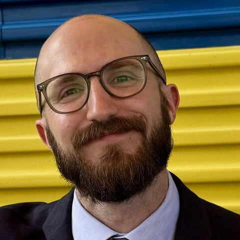 Headshot of Ryan Hansz. He wears glasses and a suit.