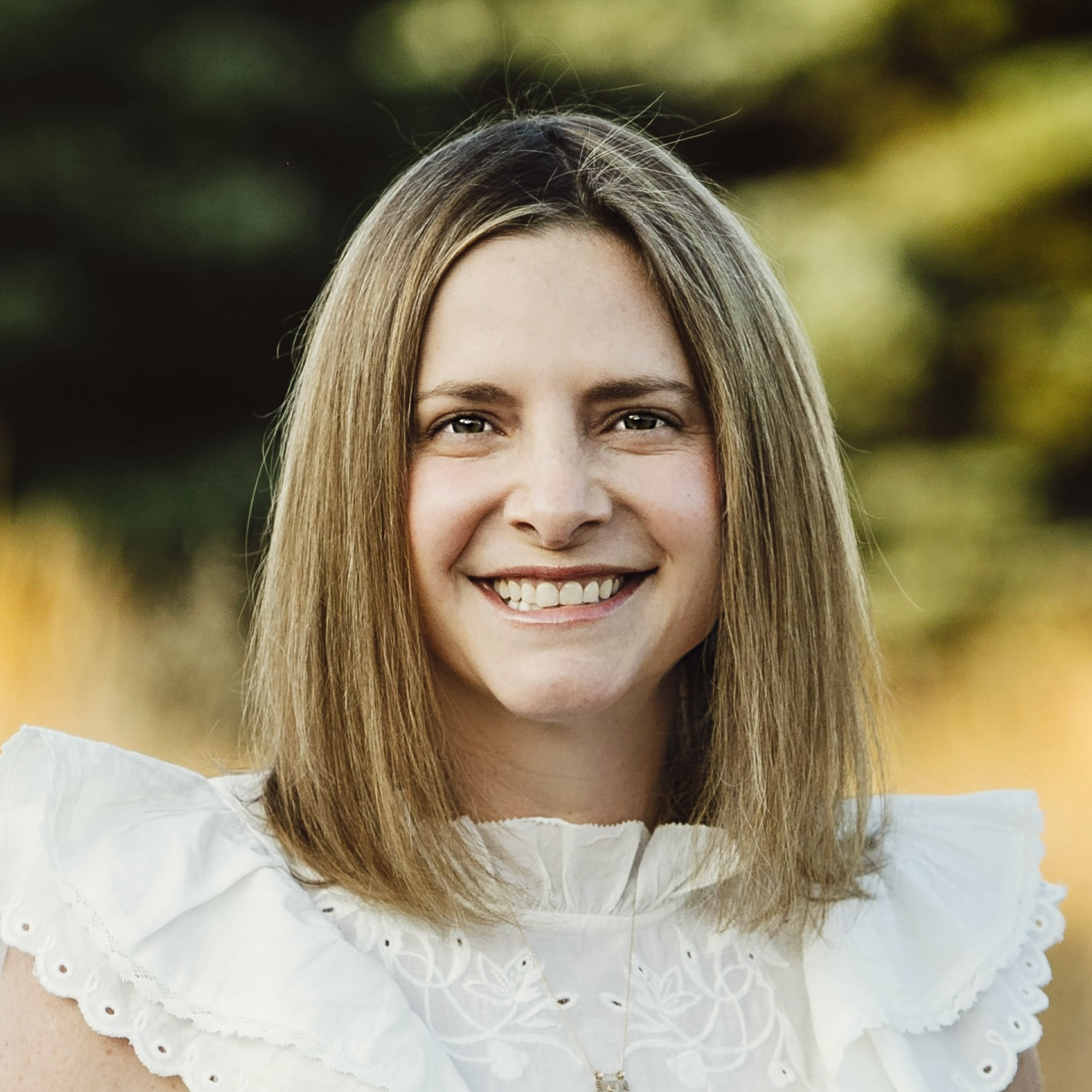 Headshot of Michaela Hackner. She has blond hair and wears a white top.