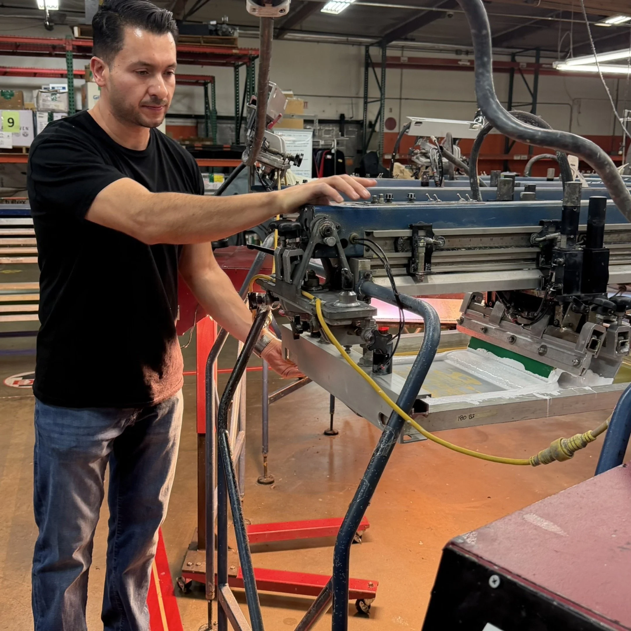 A man working with industrial machinery in a factory or workshop environment.