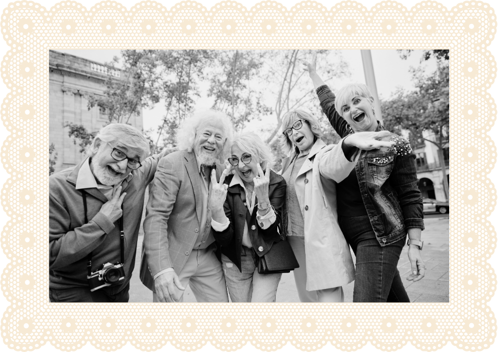 Group of five older adults smiling and having fun outdoors, with trees and buildings in the background.