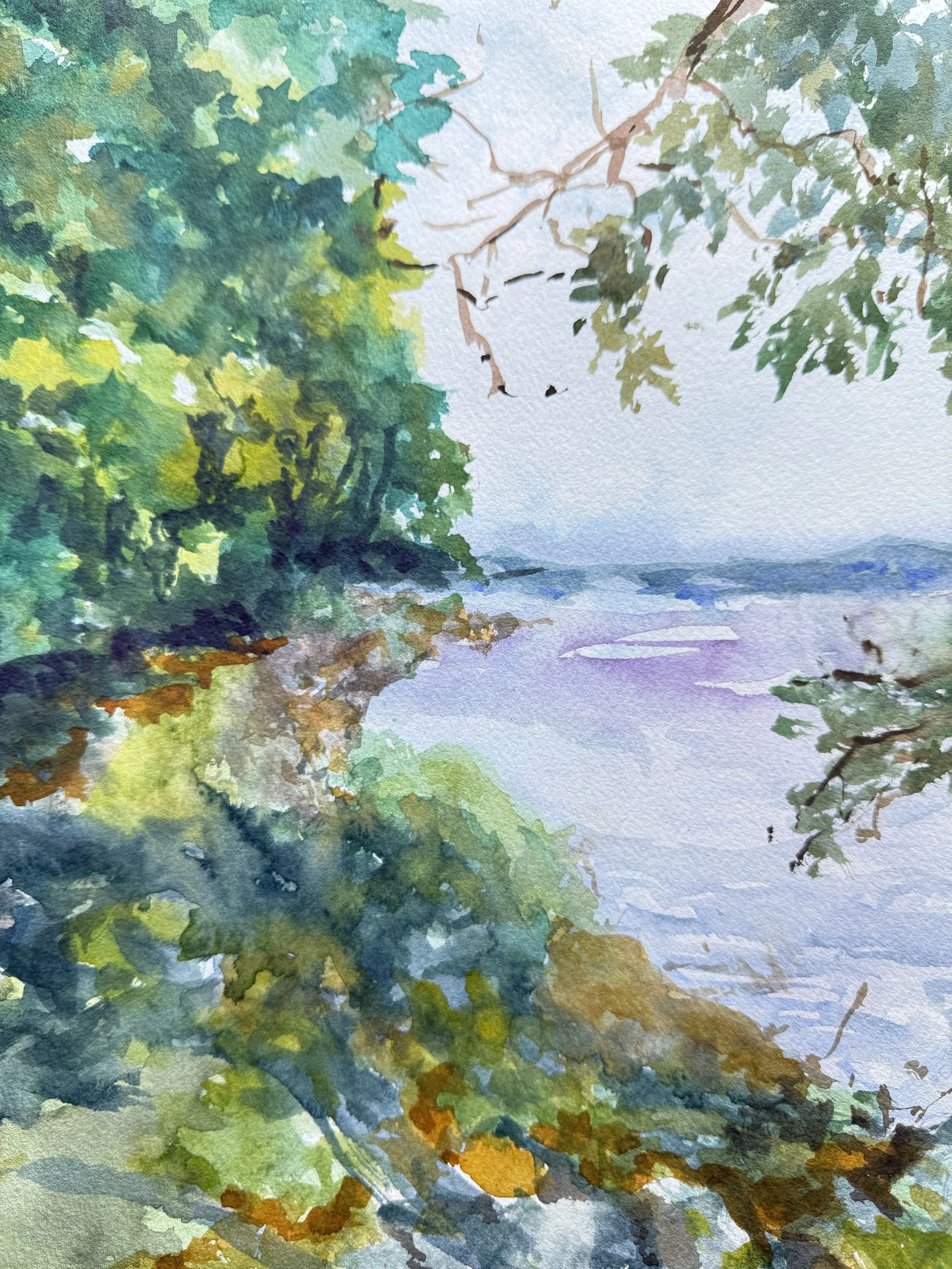 Watercolor painting of a shoreline with trees and foliage on the left and top, a calm body of water extending into the distance, and a hazy sky in the background.