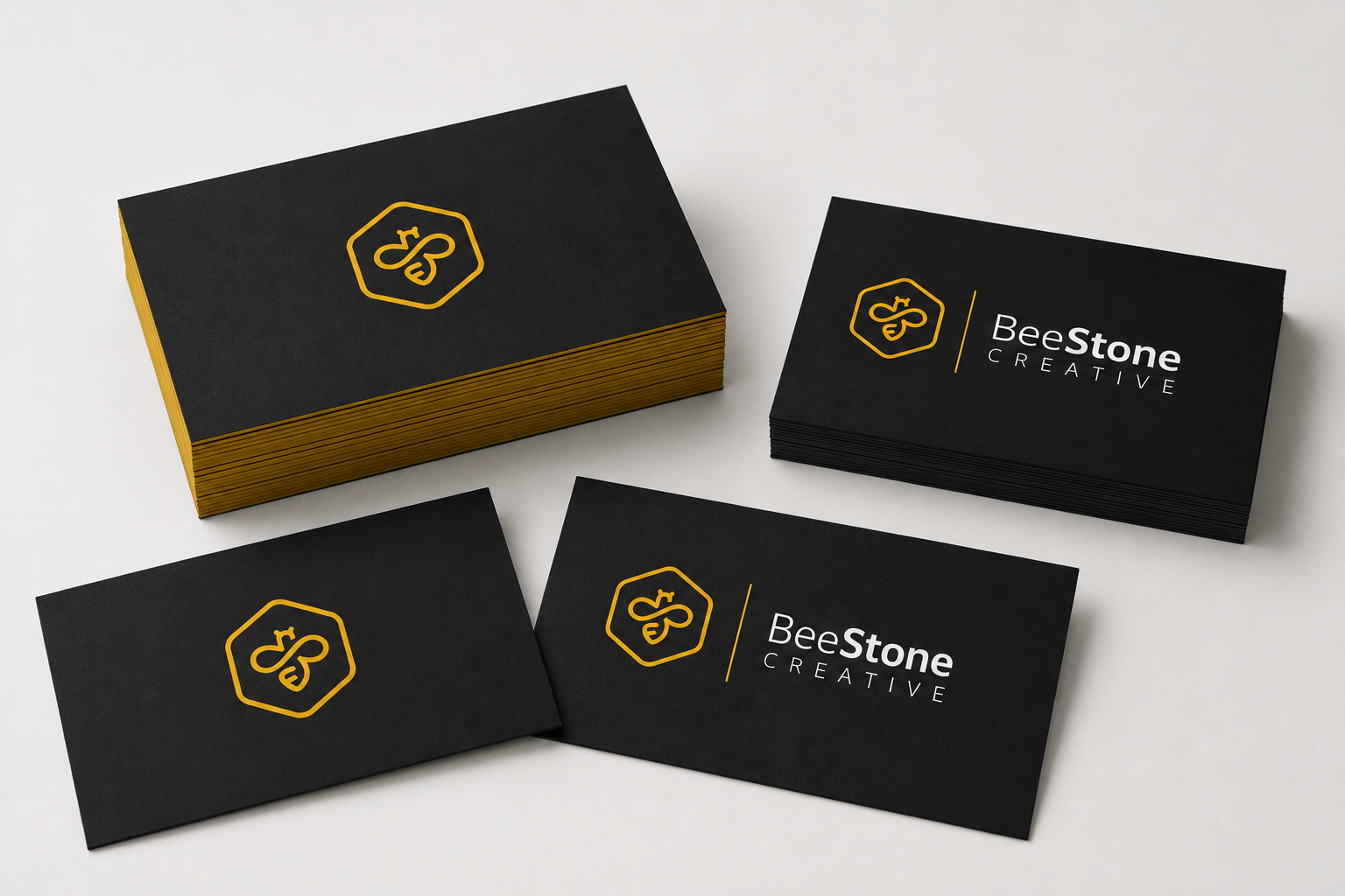 Stack of black business greeting cards printed with a gold bee logo and the text 'BeeStone CREATIVE' on a white background.